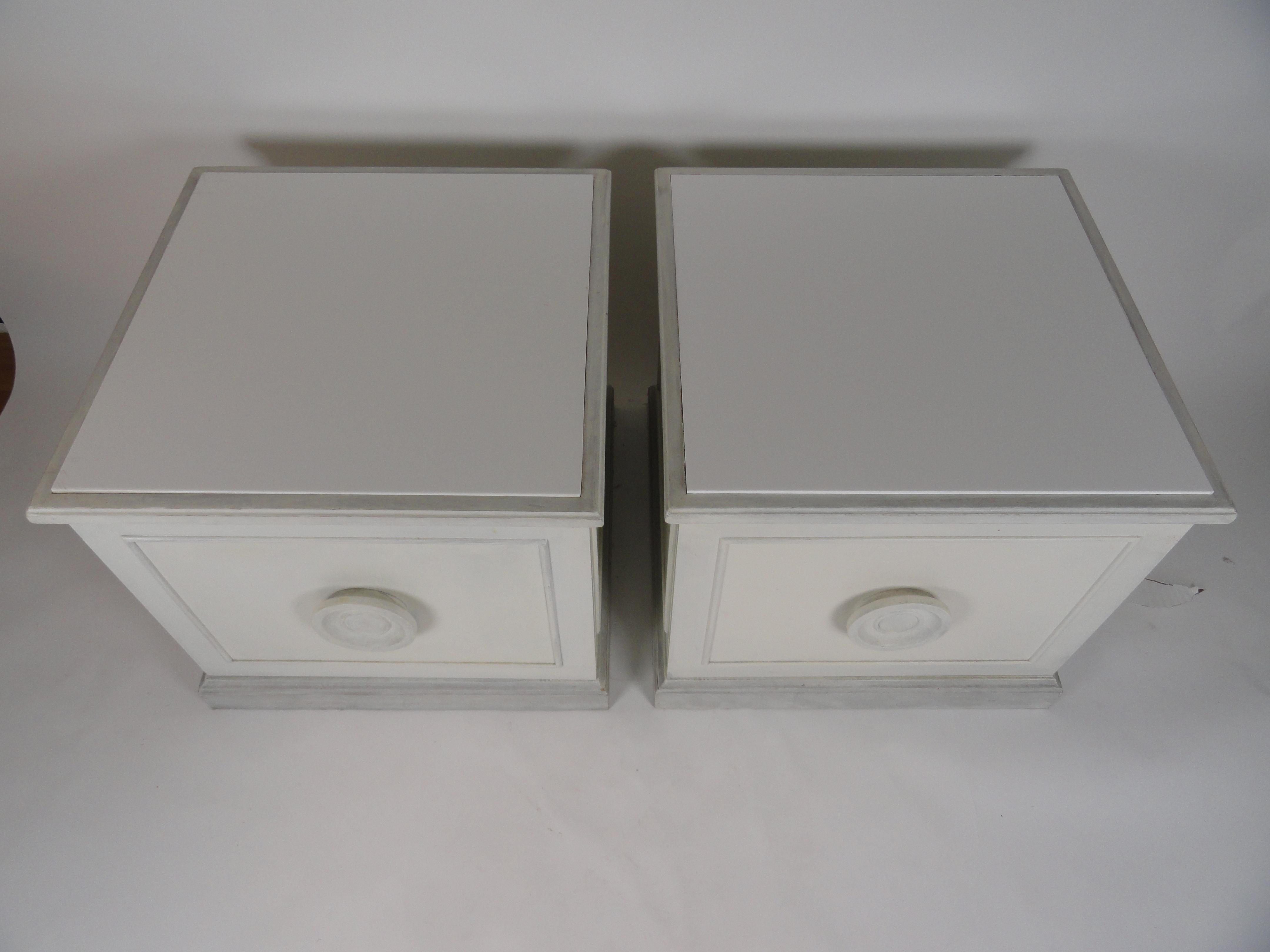 Pair of neoclassic style white painted end tables of wood with large storage capacity.
White painted pull on front. Picture frame molding on front and one side. Doors open opposite to one another.
Sturdy, heavy pieces. Single adjustable shelf