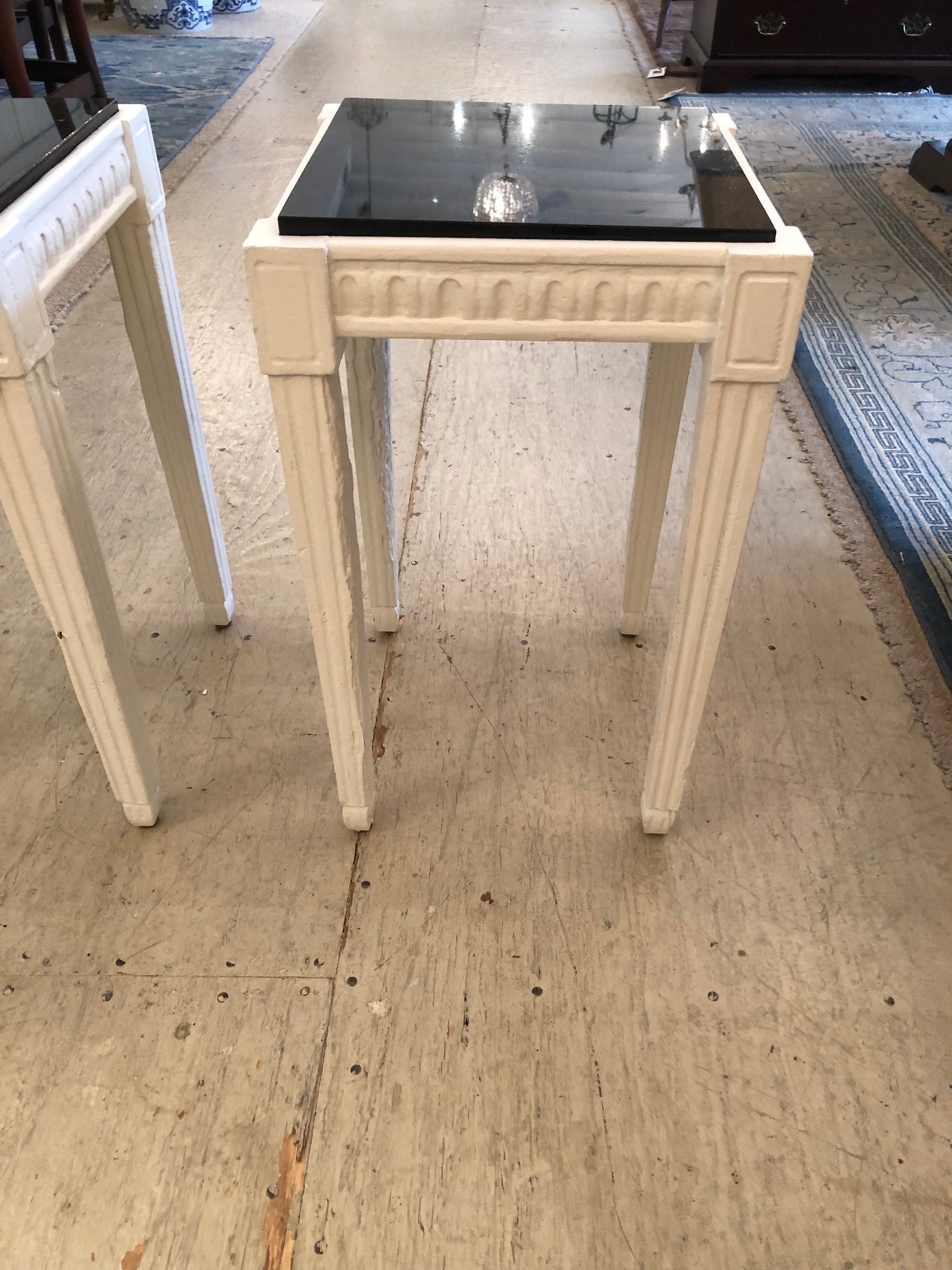 Stylish and versatile square martini tables having carved wood painted white bases and sleek glamorous black marble tops.