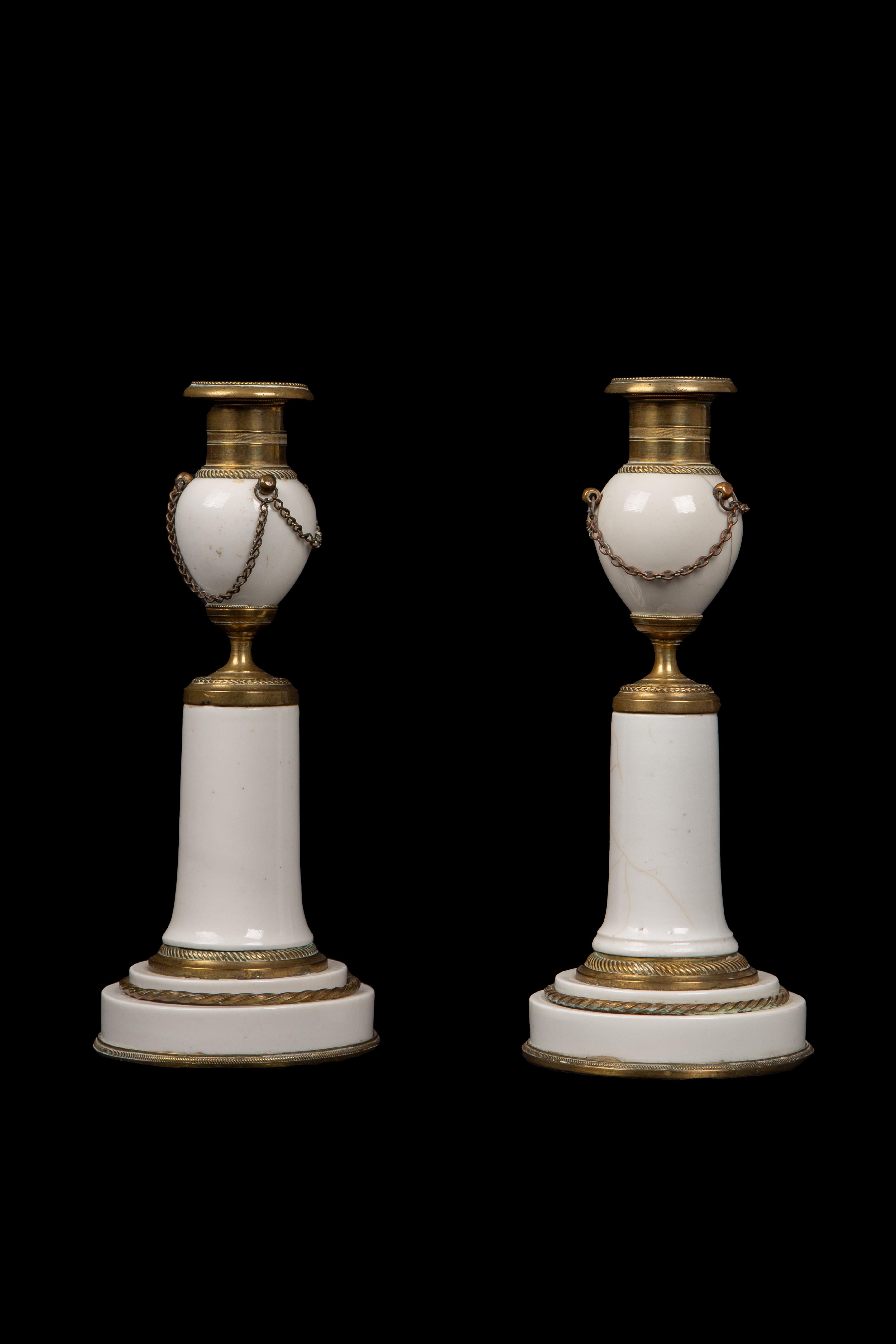 These exquisite candlesticks, originating from the late Louis XVI period, epitomize the refined and neoclassical design sensibilities of their time. Crafted from exquisite white porcelain, highly coveted for its delicate and pristine appearance,
