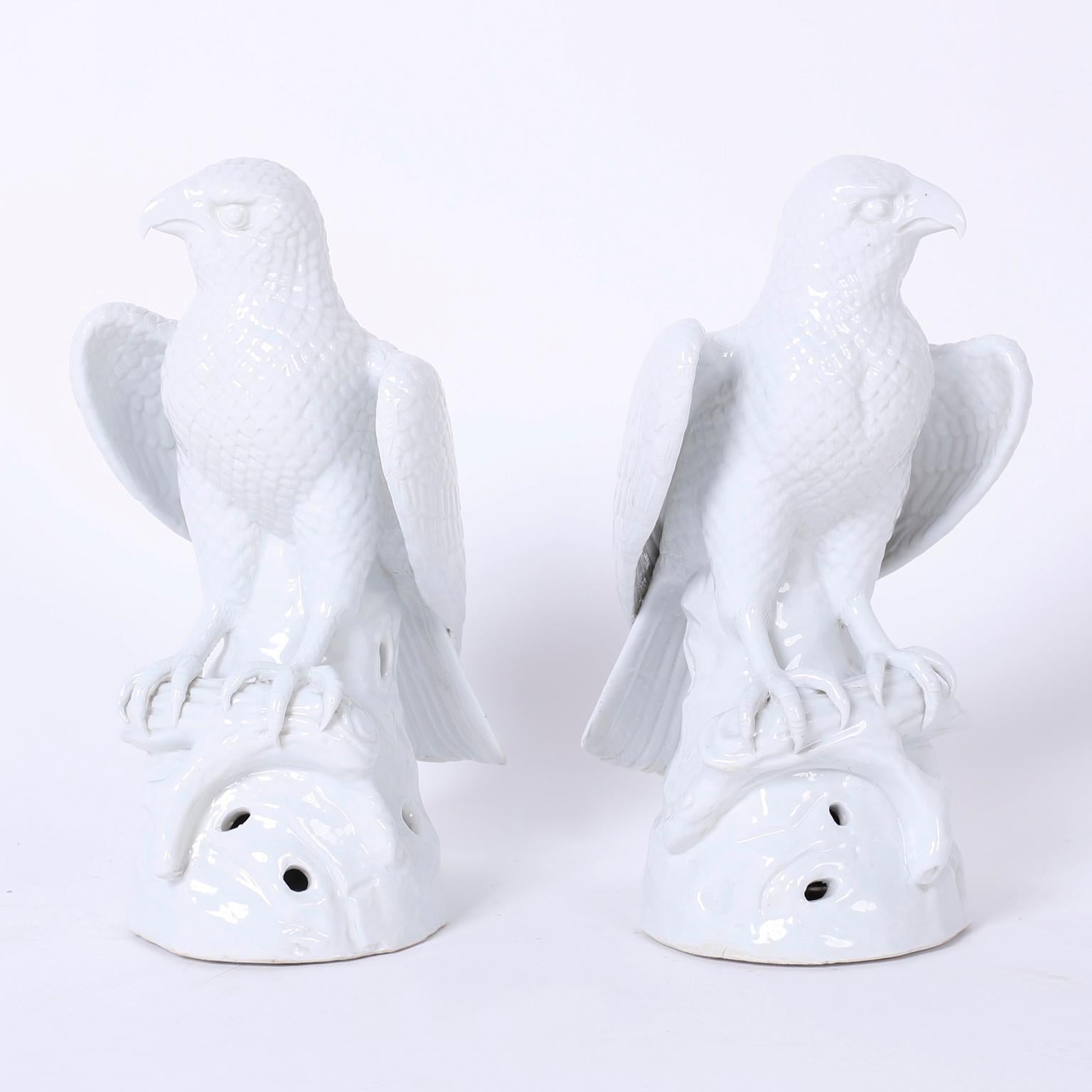 Pair of vintage porcelain birds of prey with a stark white glaze. These formidable eagles or hawks are portrayed in an alert posture perched on a branch.