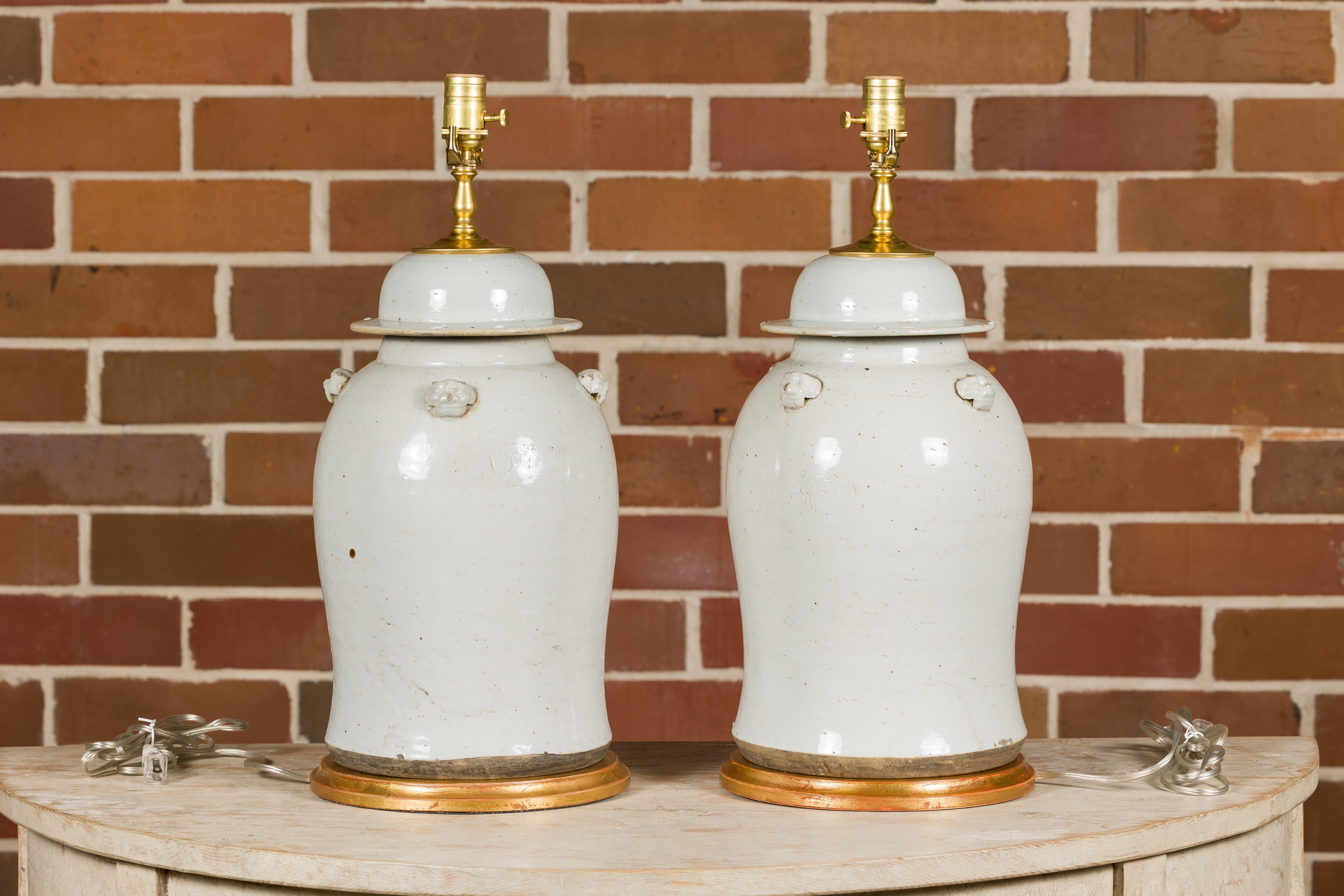 20th Century Pair of White Porcelain Lidded Urns Made into Table Lamps on Gilded Bases For Sale