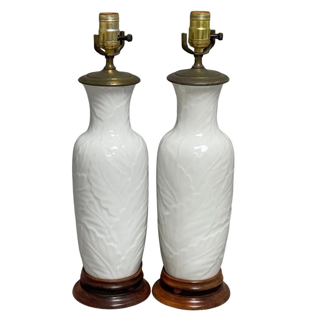 A graceful pair of table lamps crafted from white porcelain, featuring an all-over palm leaf relief design that adds texture, depth, and a touch of tropical elegance. The sculptural pattern wraps the entire body of each lamp, offering a refined yet