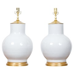 Paire de vases en porcelaine blanche transformés en lampes de table câblées aux États-Unis sur bases en bois doré