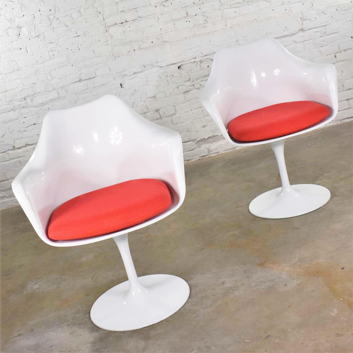 Handsome pair of replica Saarinen style tulip swivel chairs in white with bright red cushions. They are in wonderful used condition. They do have small nicks and dings around rim of base that have been touched up. Please see photos, circa early 21st