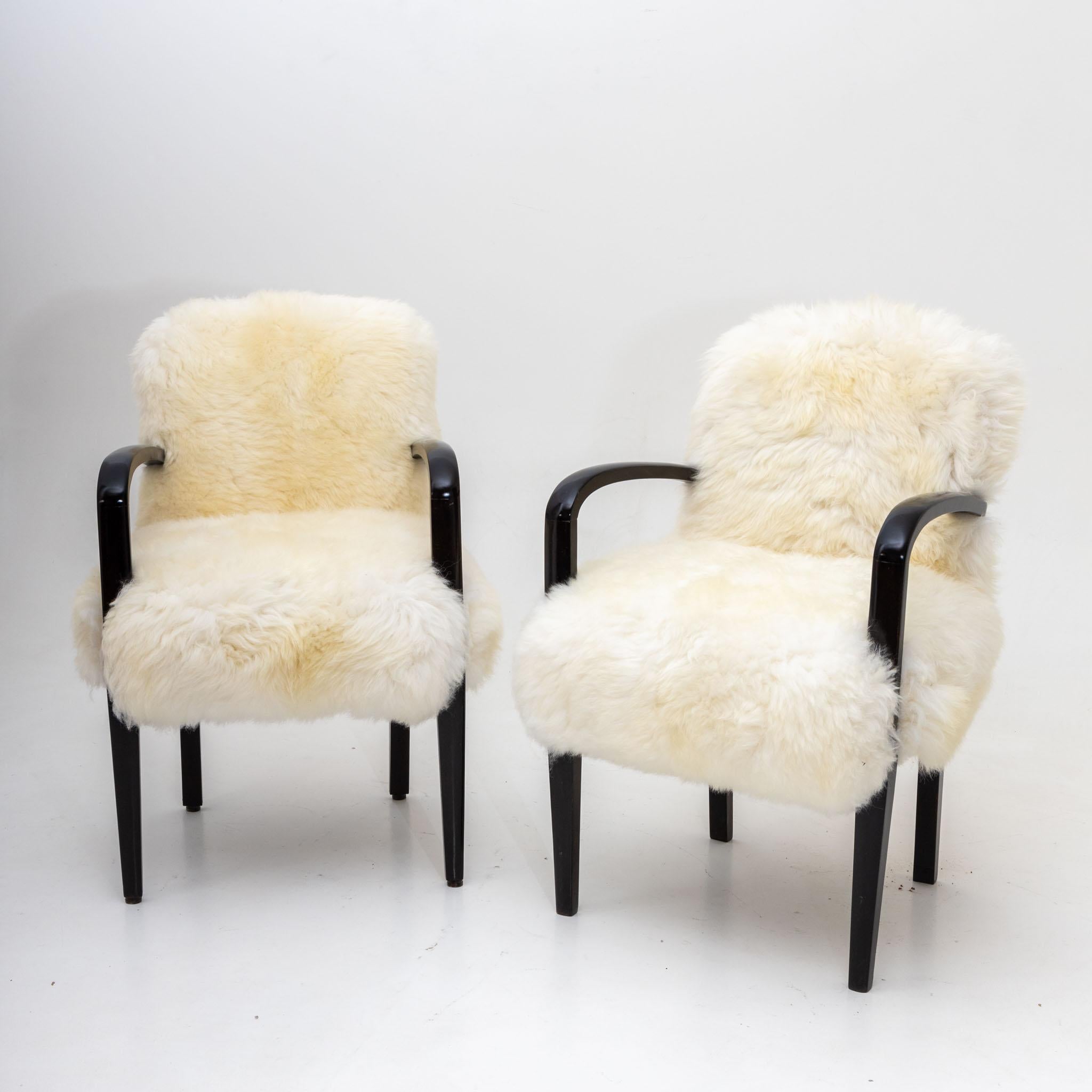 Pair of sheepskin armchairs with black legs and armrests. The armchairs have been newly covered with a genuine sheepskin and hand-polished.