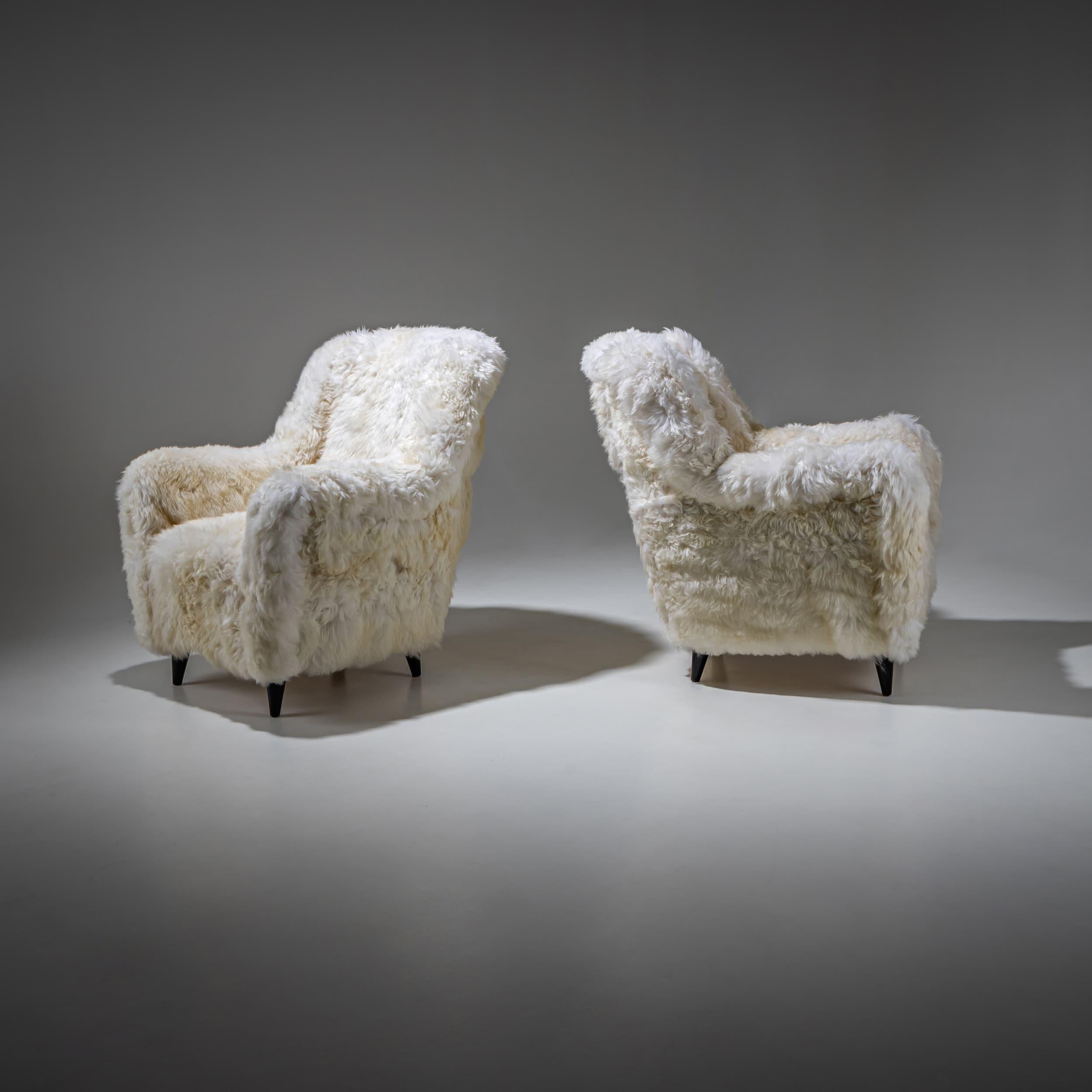 Paire de chaises longues italiennes du milieu du siècle sur pieds coniques noirs, nouvellement recouvertes de peau de mouton véritable.