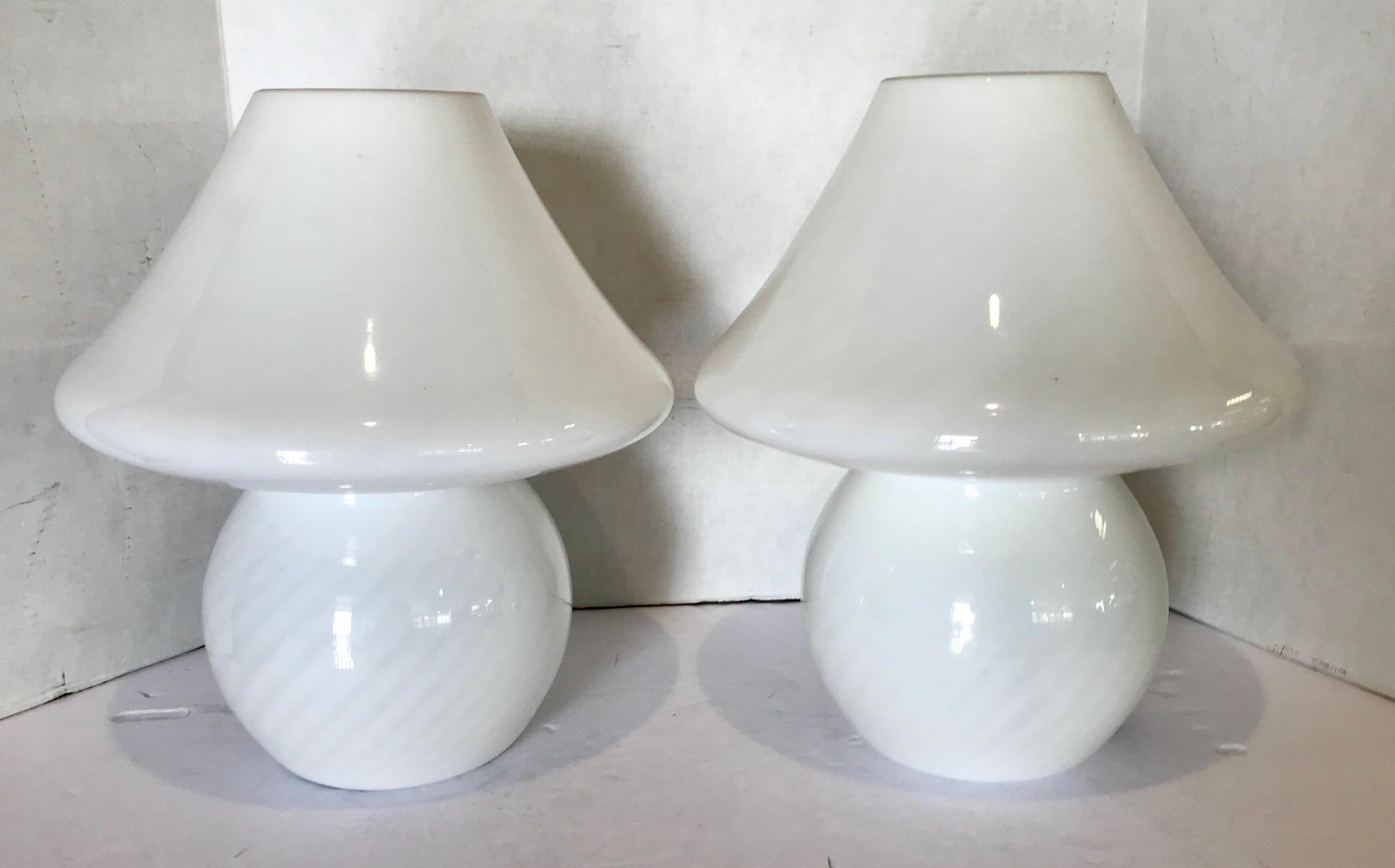 Pair of vintage venini Murano glass mushroom lamps have a white swirl pattern all around. Each lamp is made of one piece of hand blown glass and takes one standard bulb up to 100 watts. They are wired and in working condition.