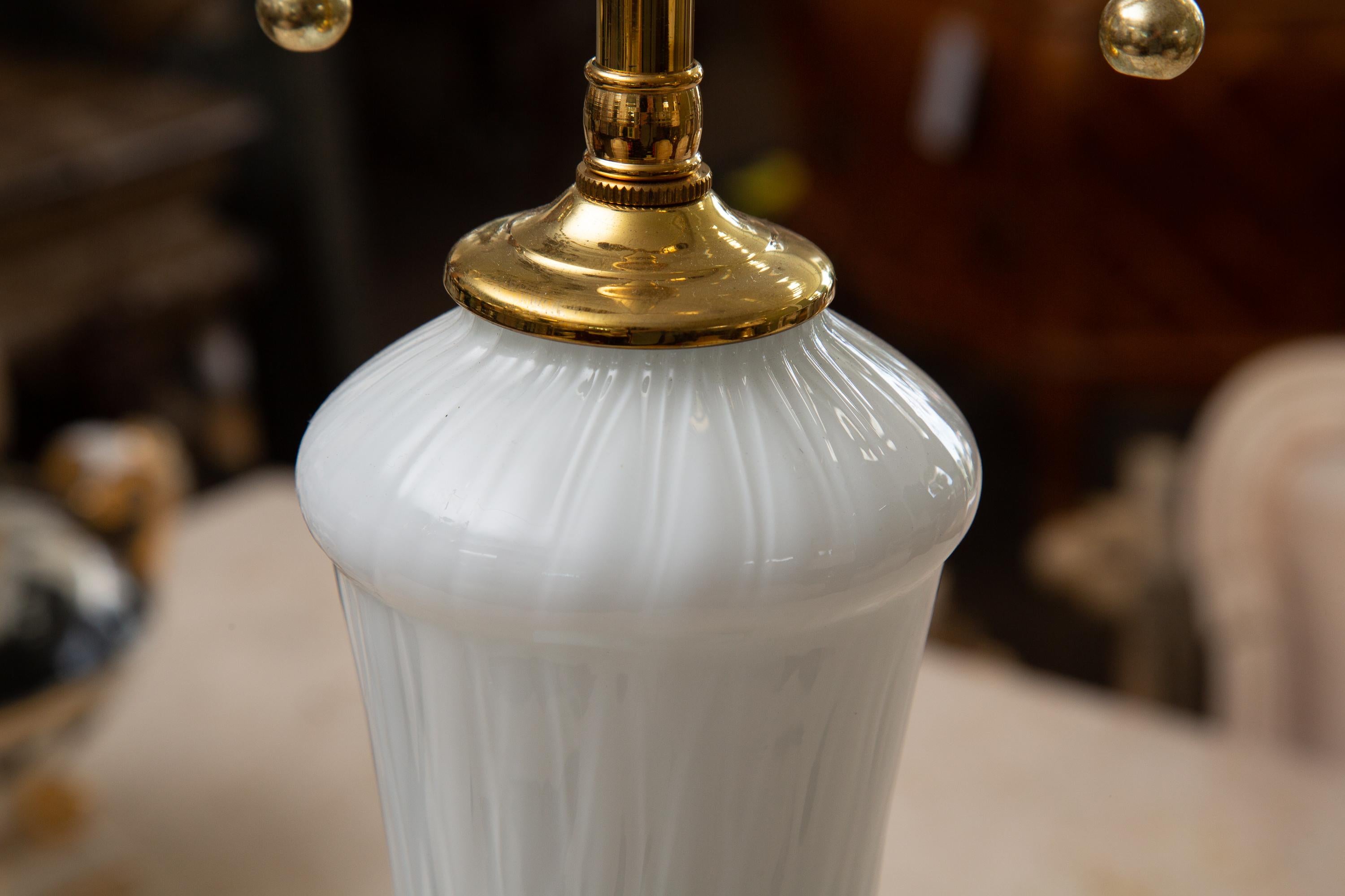 This is a very sophisticated pair of white translucent Murano lamps, with a long slender neck expanding to a bulbous form and situated on a circular stepped brass base, mid-20th century.