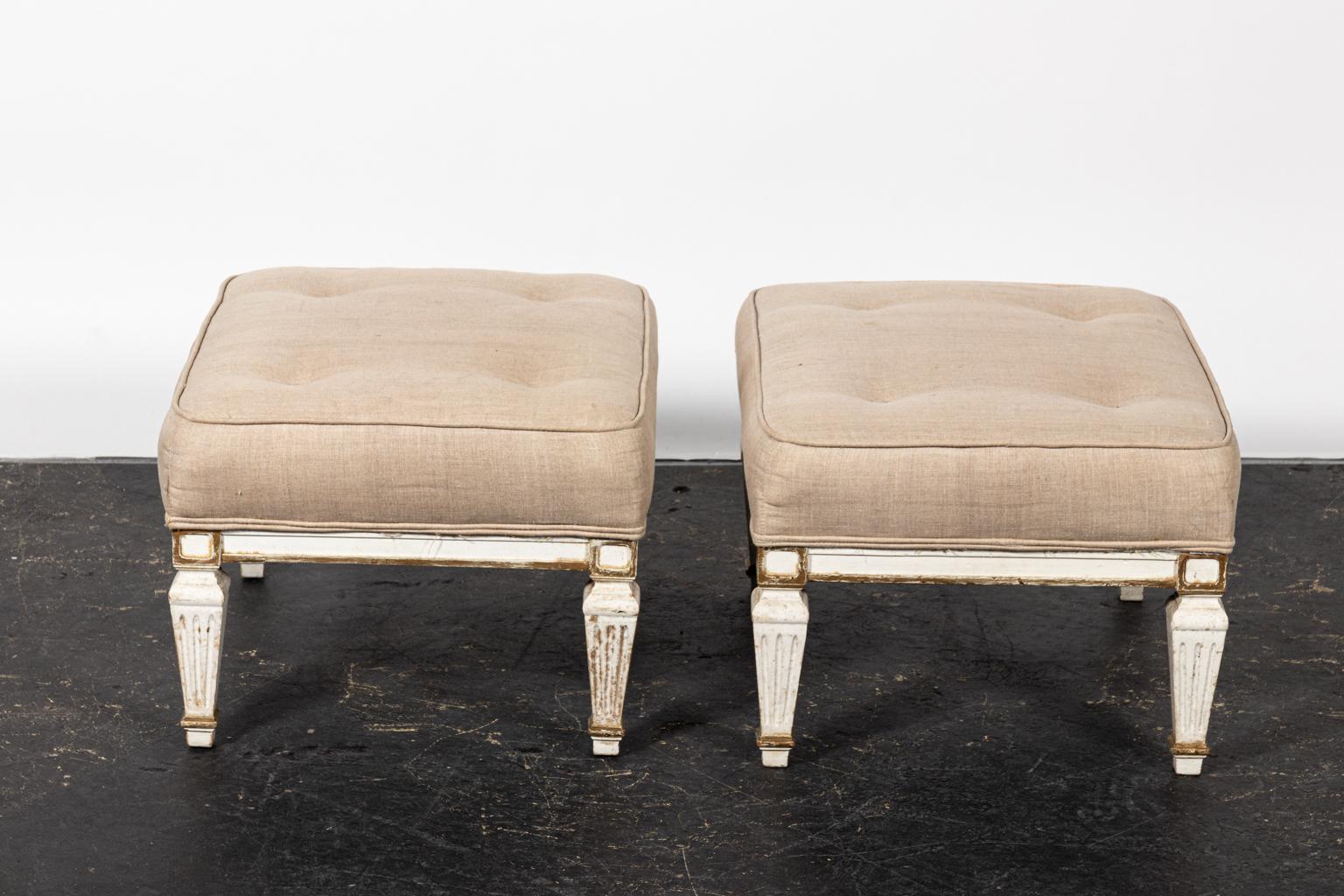 Pair of white upholstered benches with tufted seats and turned legs. Please note of wear consistent with age including paint loss and stains on the upholstery.