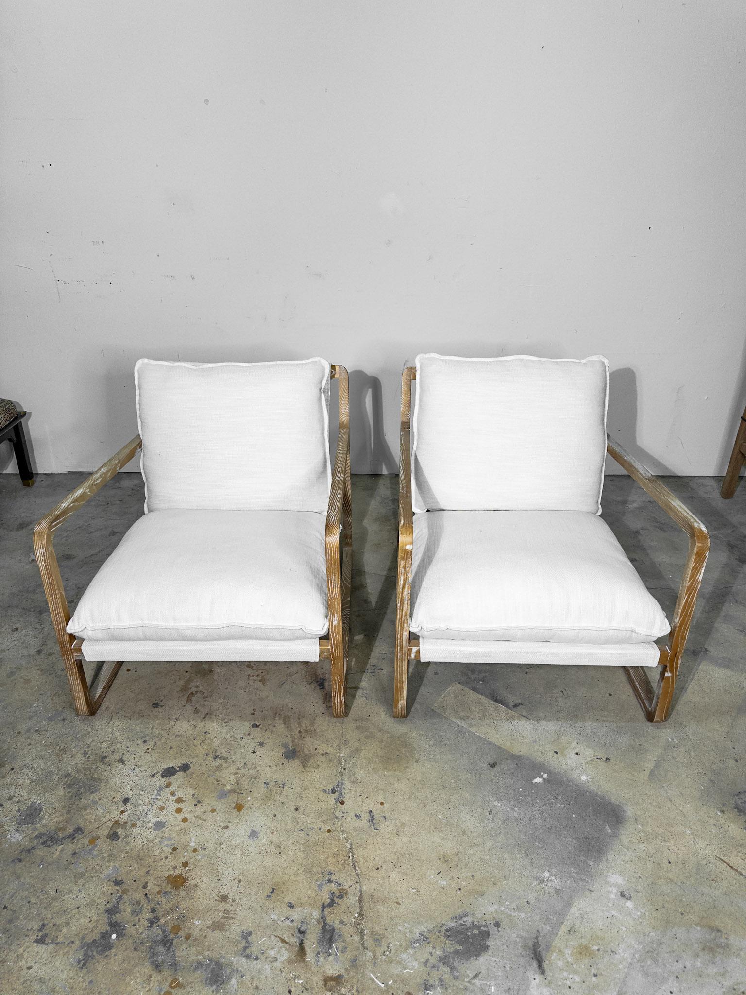This pair of white upholstered sling chairs epitomizes contemporary elegance and comfort. Each chair features a streamlined sling design, characterized by its minimalist structure and clean lines. The white upholstery, made from high-quality,