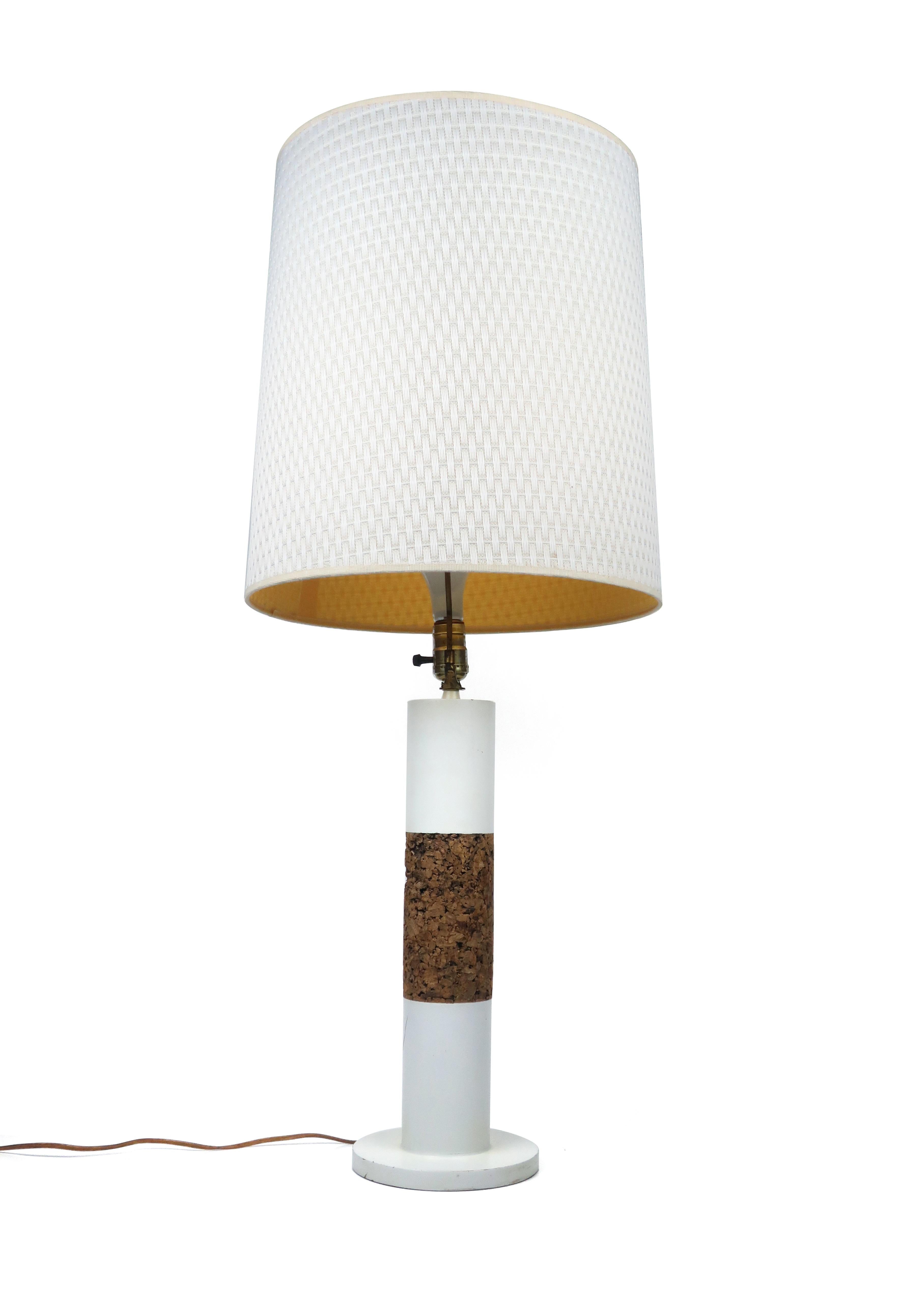 A stunning matched pair of vintage white cylindrical table lamps with cork bands and original white woven fabric shades. Each lamp has a three way switch.

In vintage condition wear consistent with age and use. Includes a few marks to white paint