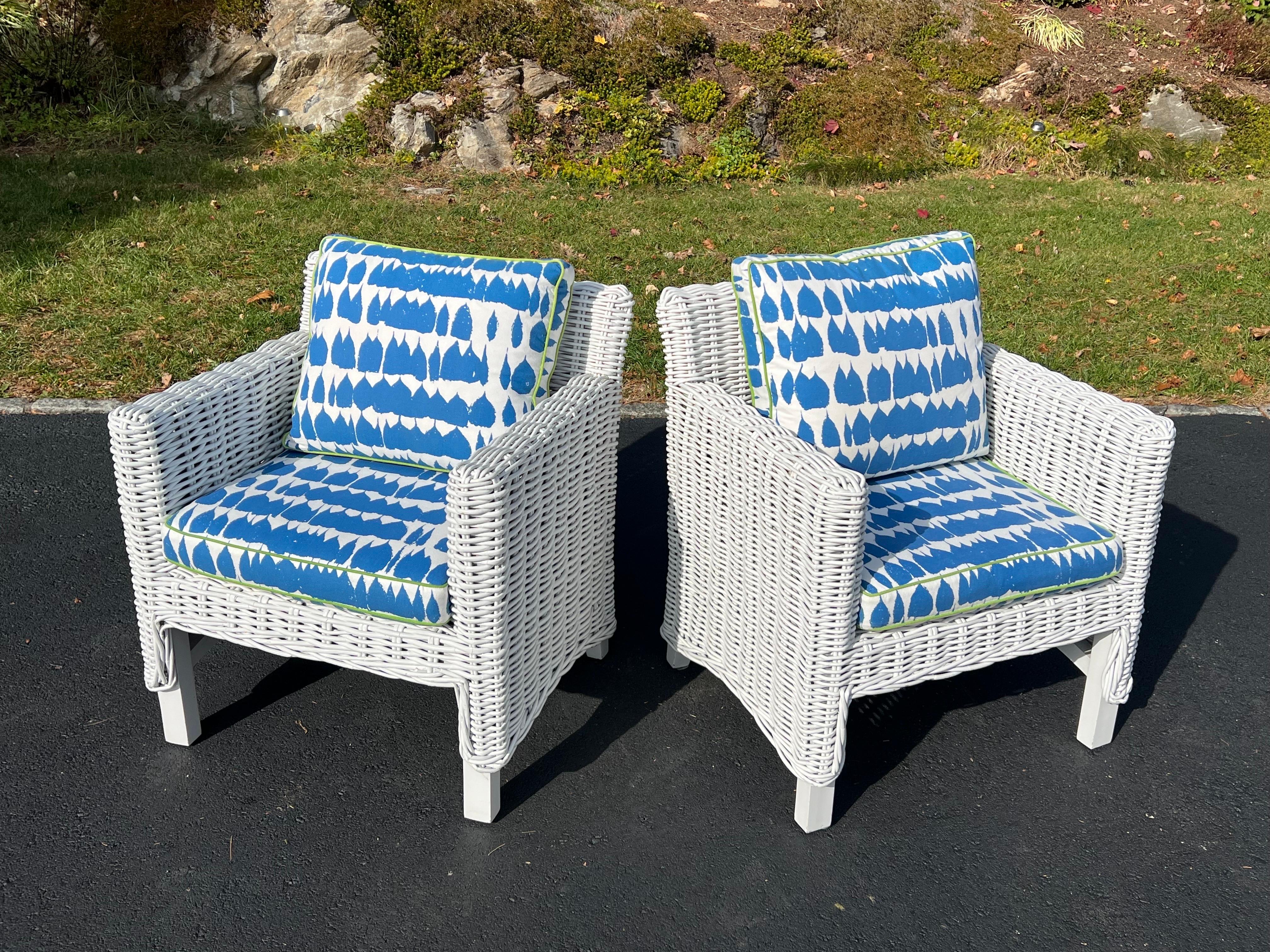 Coppia di sedie club in vimini bianche con cuscini rivestiti su misura. Perfetto per una veranda o una casa al mare. Una bella trama spessa in vimini con un'ottima consistenza. Tessuto di tendenza con profili a contrasto. Un cuscino superiore è più