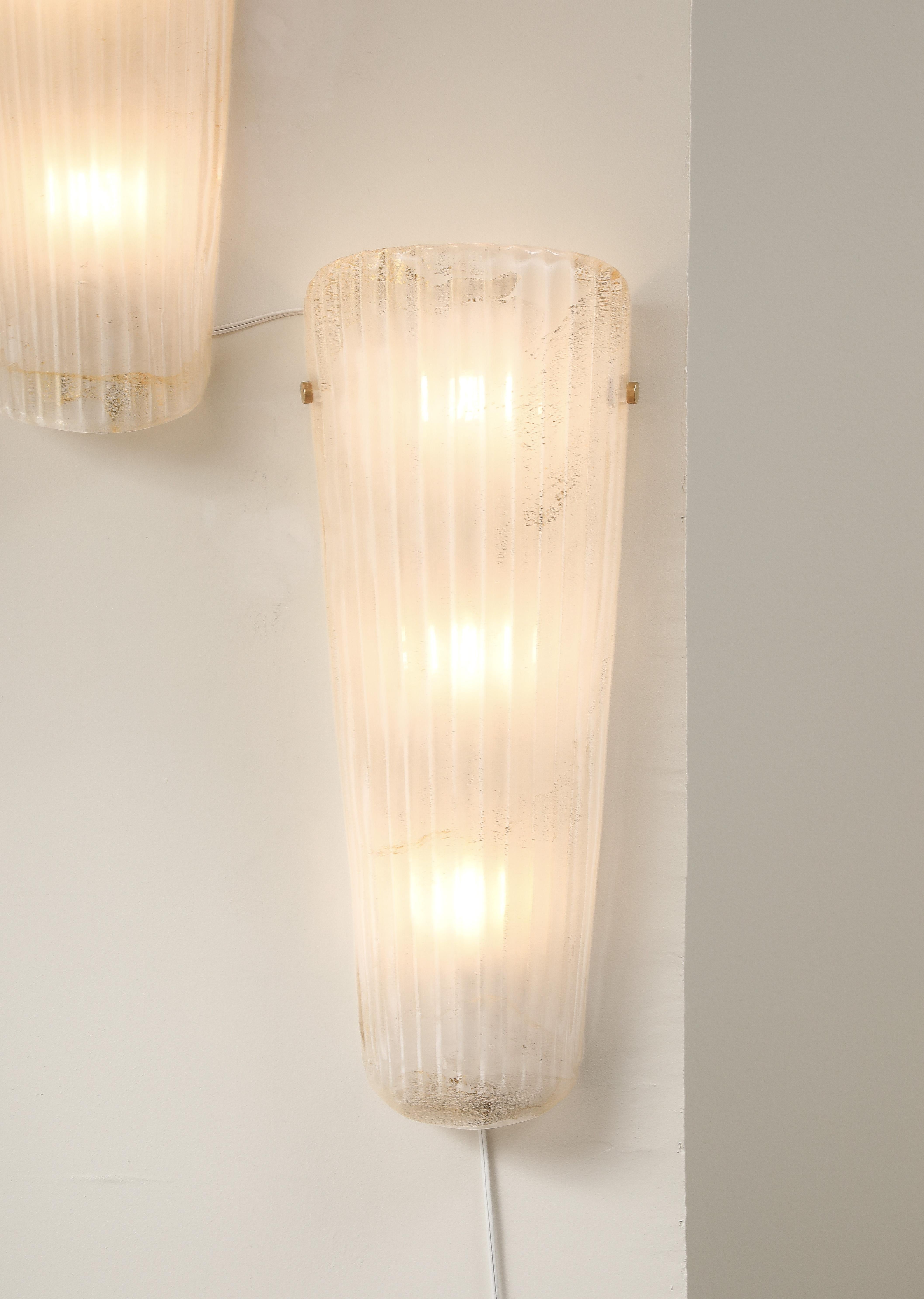Elegante e scultorea, questa coppia di appliques in vetro di Murano realizzate a mano presenta una raffinata forma a 