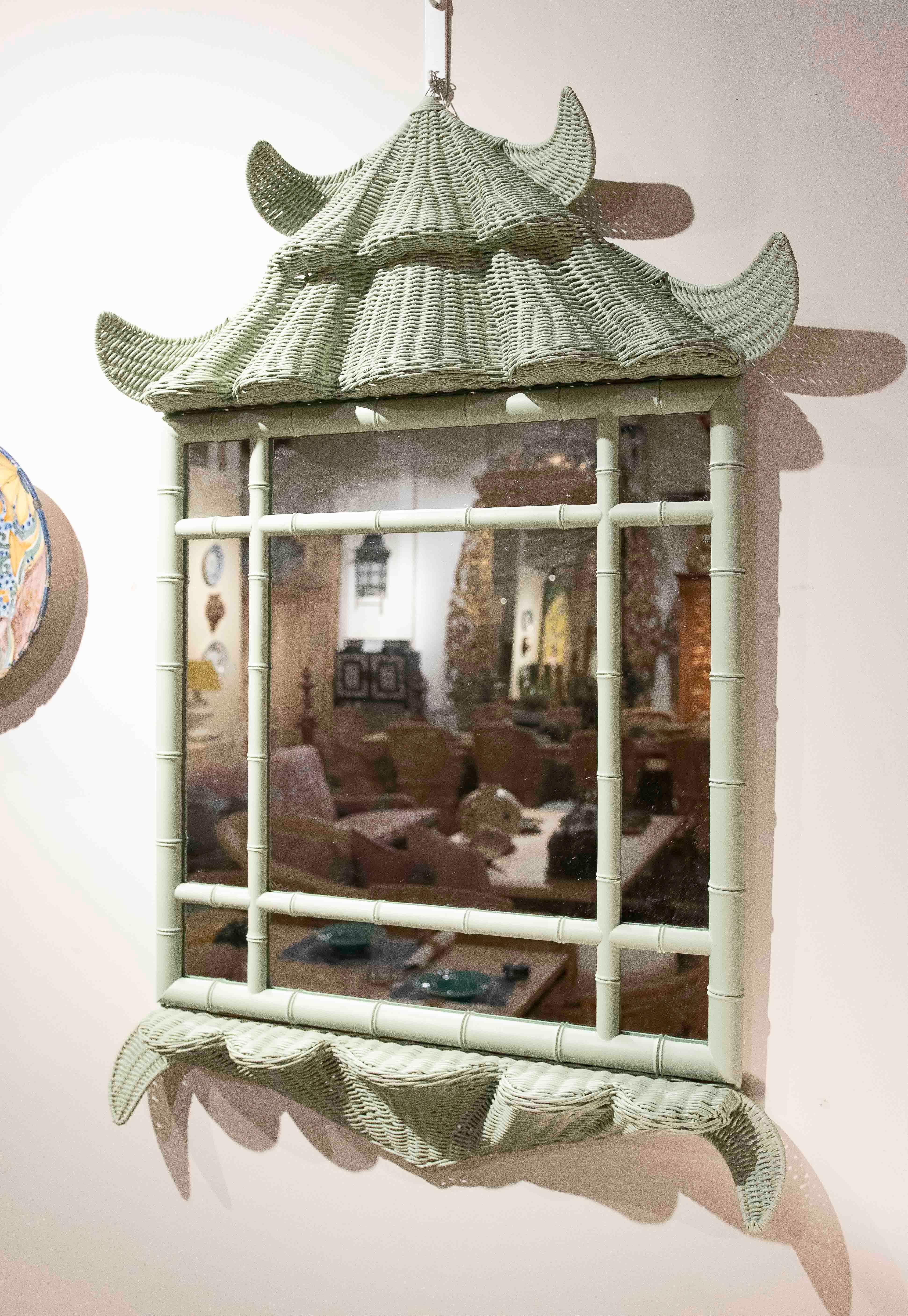 A pair of decorative mirrors with a rattan frame painted in a delicate mint green. Their design is inspired by traditional Asian pagoda-shaped architecture, highlighting the wavy details at the top and bottom and the frame imitating bamboo