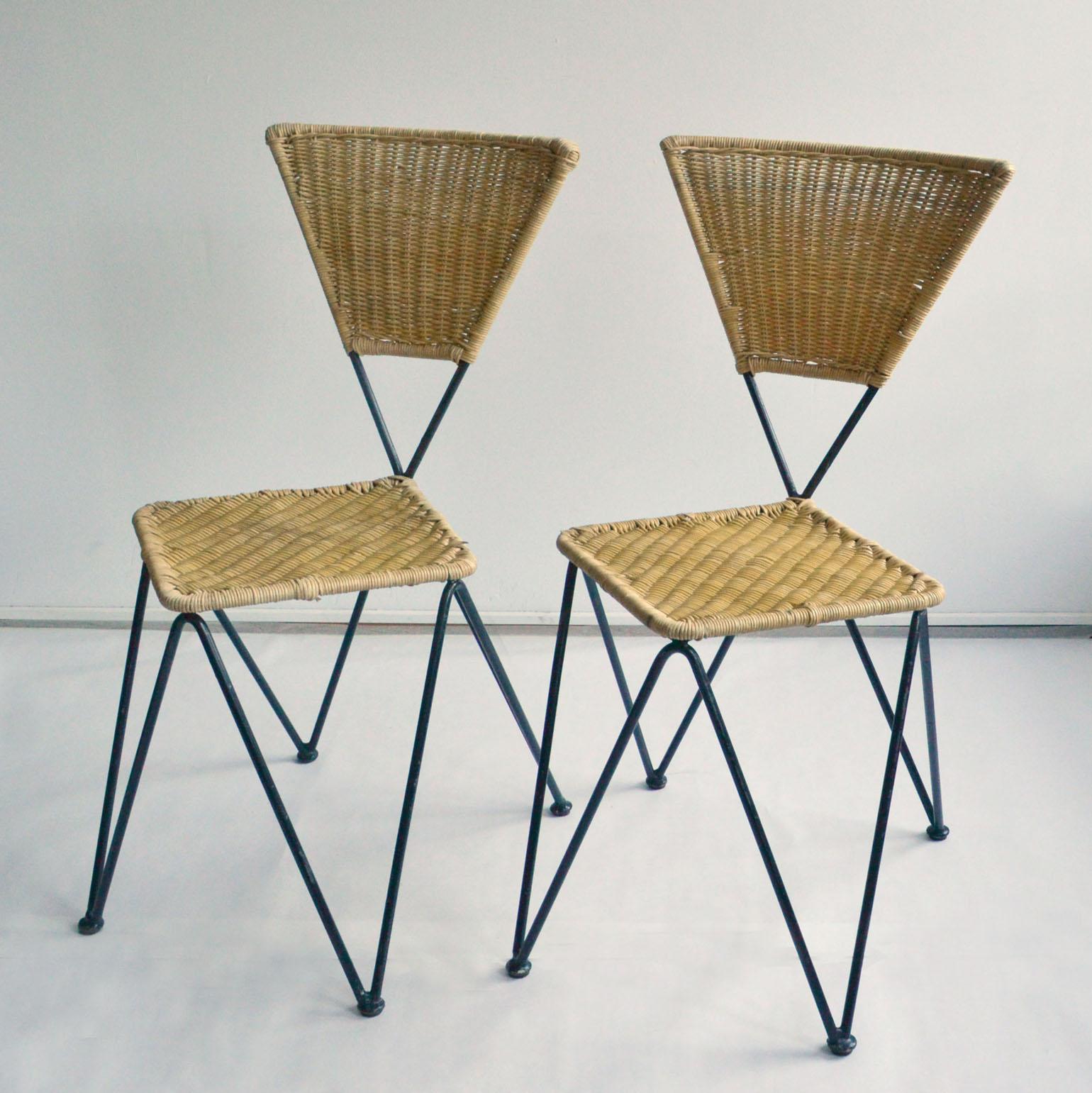 Set of 2 geometric wicker and metal dining chairs designed by Karl Fostel Erben and executed by Sonett, Vienna, circa 1950. The frame is made of black lacquered iron, the seat and back are woven in cane. These comfortable chairs can stack. 
The