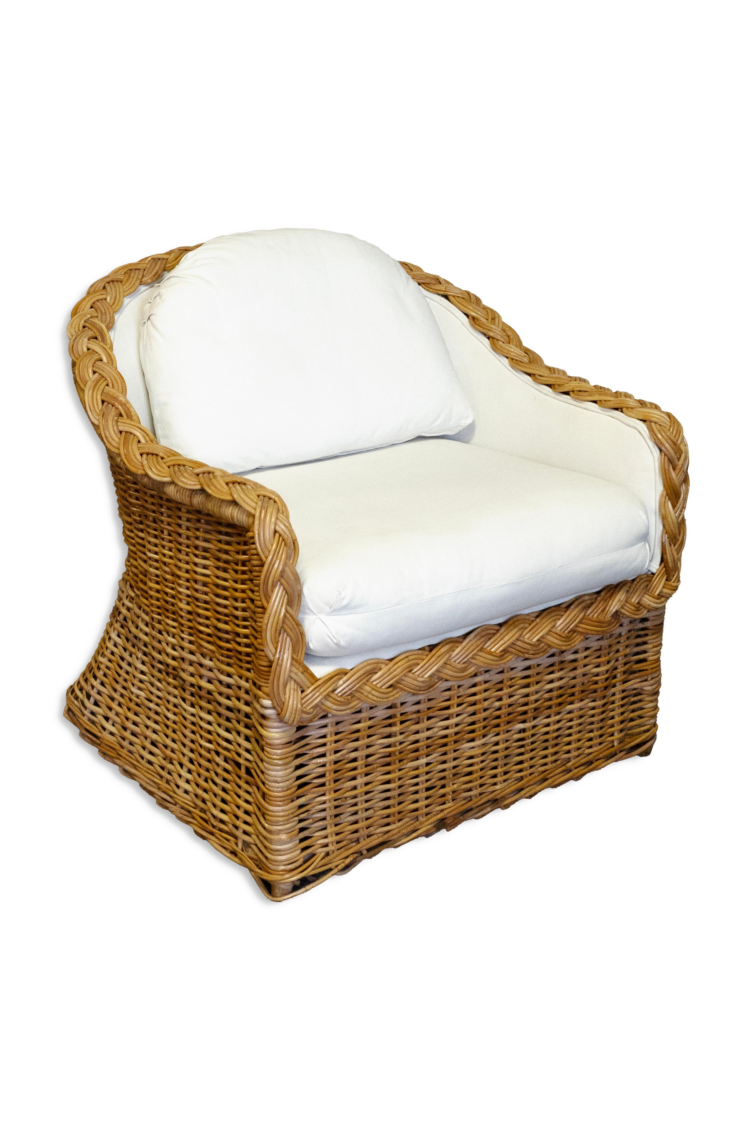 A pair wicker rattan lounge chairs from The Kreiss Collection, complete with an ottoman. These versatile chairs can be used indoors or would make a wonderful addition to a sunroom or porch. They are crafted from woven wicker and rattan, featuring