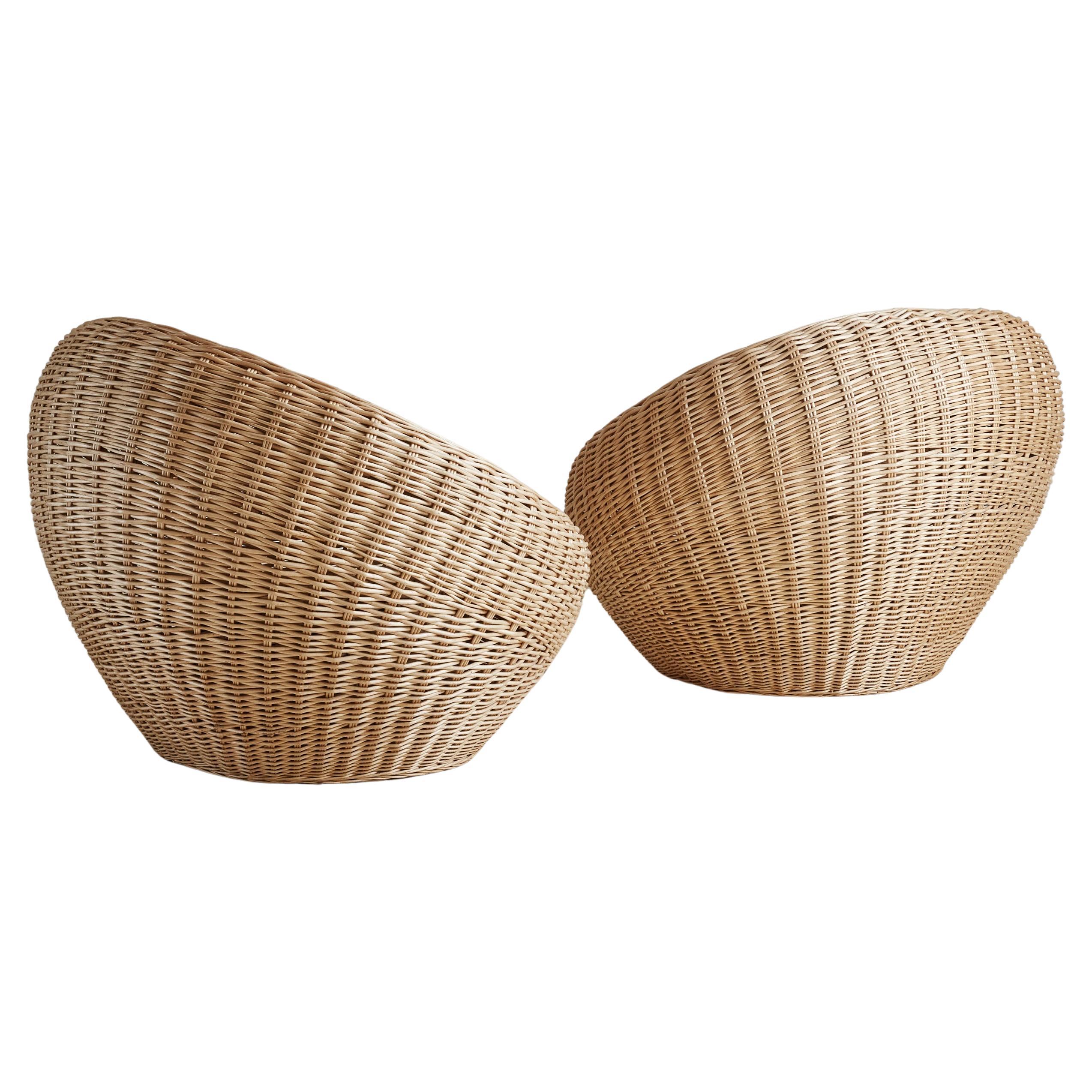 A gorgeous pair of rounded wicker lounge chairs in the style of Japanese modernist designer Isamu Kenmochi. These organic chairs are sculptural and elegant, featuring tightly woven rattan in a beautiful blonde hue. Circular cushions in white woven