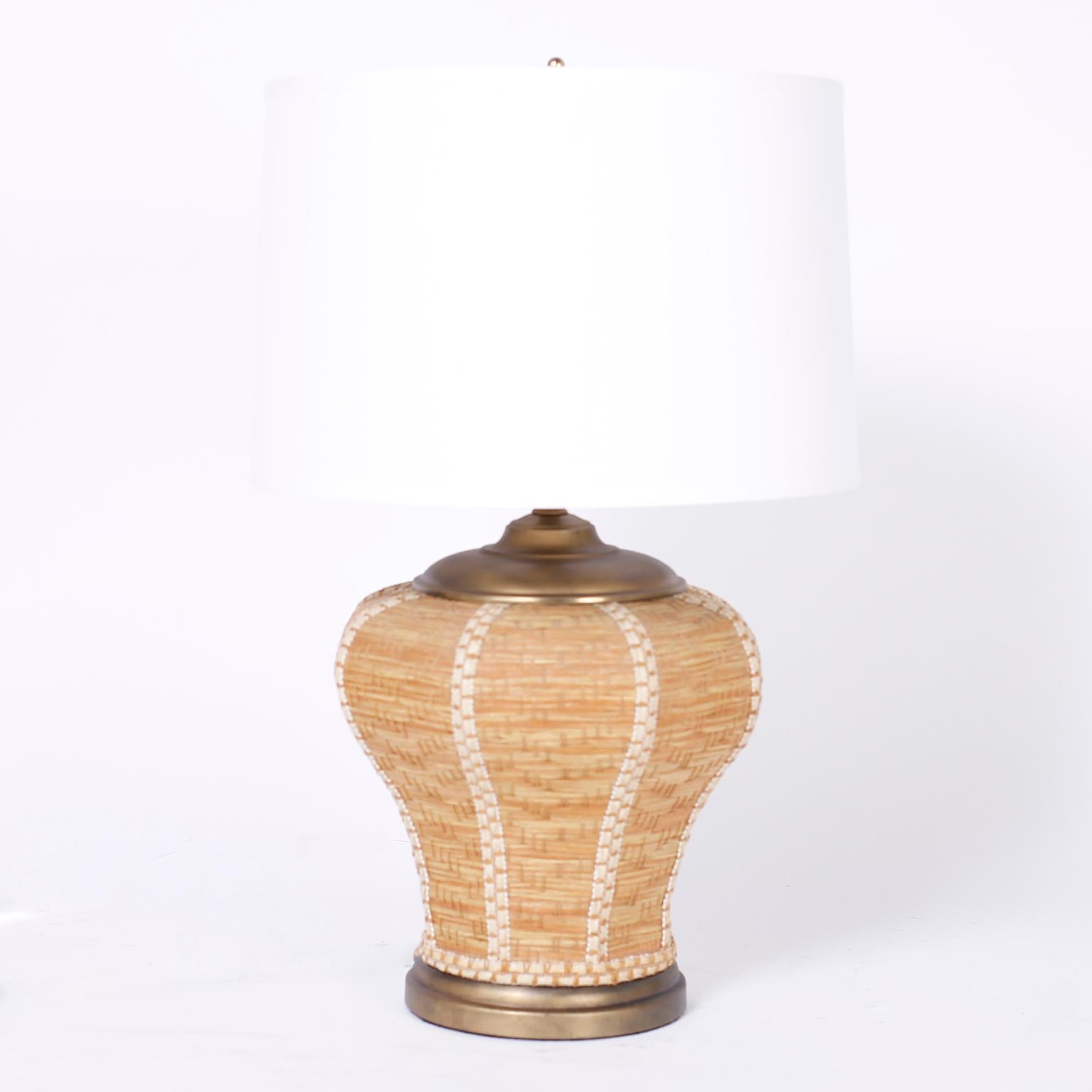 Pair of midcentury table lamps with Classic form and organic ambiance crafted in wicker with an unusual weave pattern and burnished brass caps and bases.