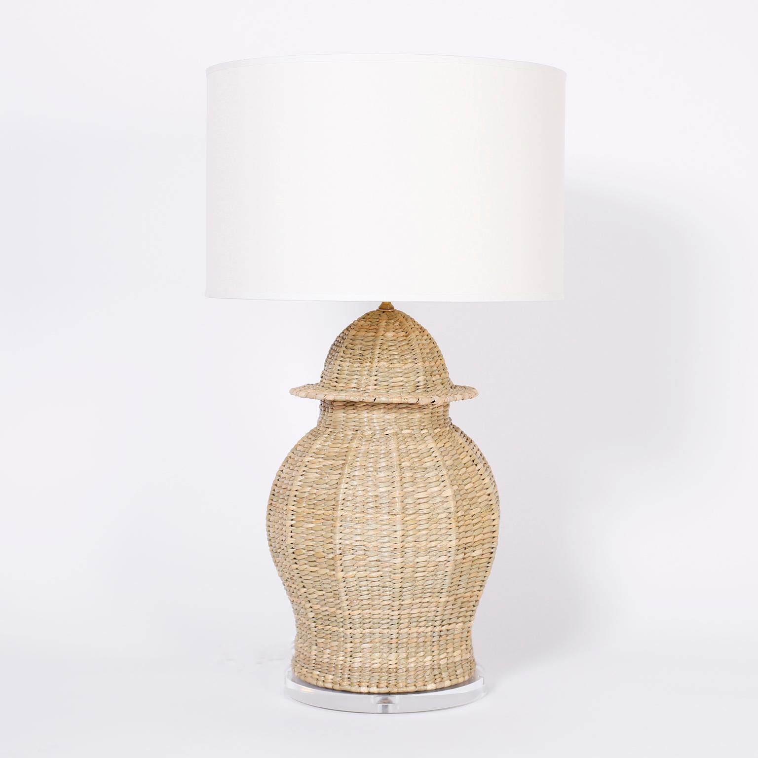 A pair of Classic Chinese ginger jar form wicker table lamps crafted with a metal frame wrapped with reed, in the style of Mario Lopez Torres, and presented on Lucite bases. Exclusively designed and offered by F. S. Henemader Antiques from the