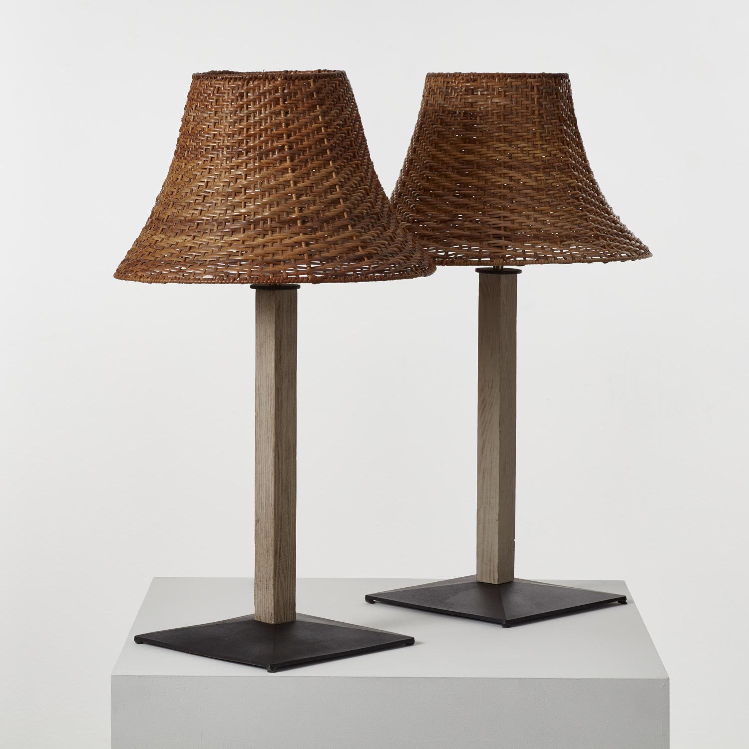 A pairing of wood, wicker and metal. Each lamp is braided in a herringbone twill weave for its shade, gently curving outward as light perforates through, casting warm refracted rays. The slender stand rises with a subtle lip at its top, column-like