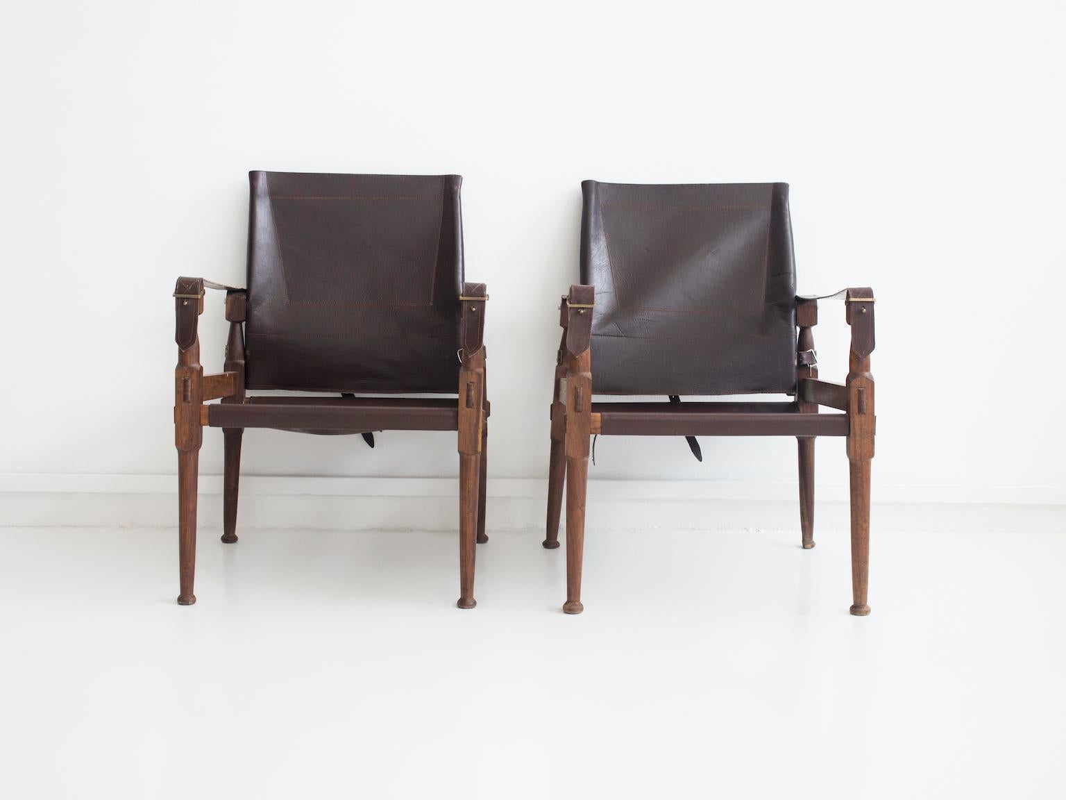 Pair of 'Safari' chairs originally designed by Wilhelm Kienzle in 1928. Frame made of stained oak, dark cognac-colored leather seat and back with brass details.