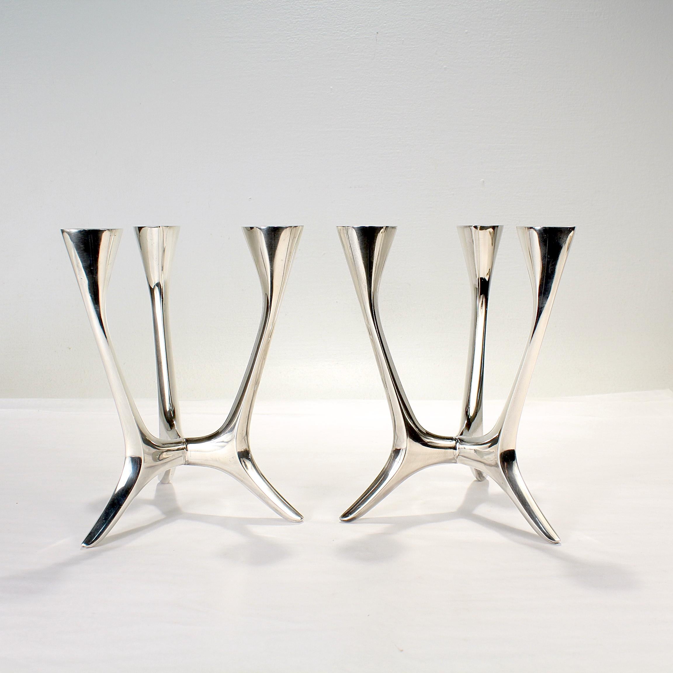 A fine pair of German Mid Century modern three-light candelabra.

By M.H. Wilkens and Söhne. 

Each consisting of 3 joined arms supported by a flaring base and terminate in oval or navette shaped flaring candle cups. 

Simply wonderful Modernist