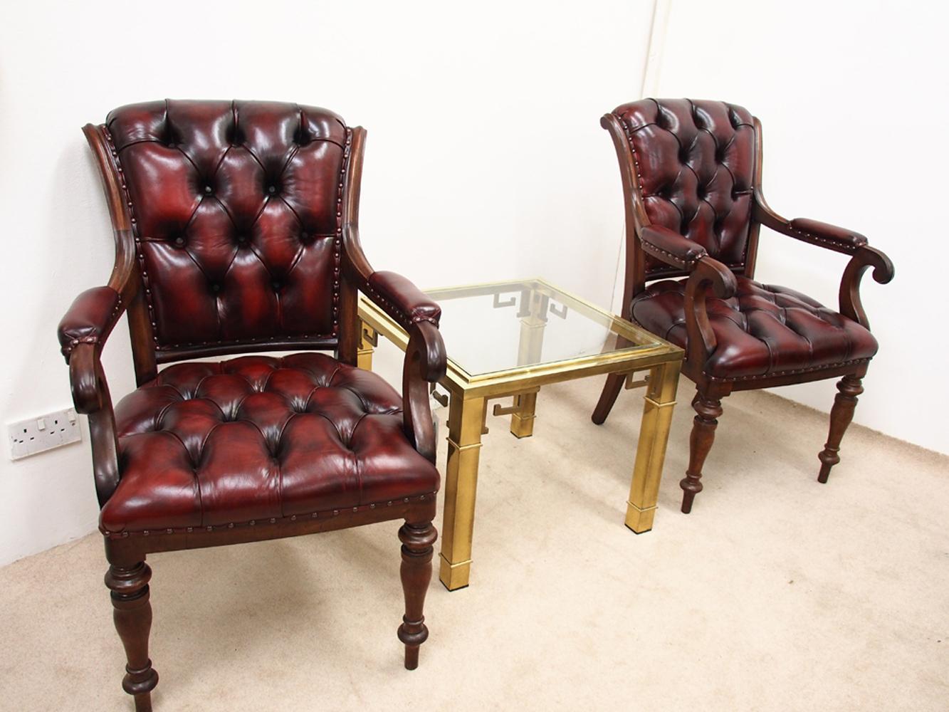Pair of William IV mahogany library chairs, circa 1840. The mahogany framed chairs have a shaped, flared back, and have been recently reupholstered in deep buttoned burgundy leather. With a slight scroll to the top of each frame, continuing down to