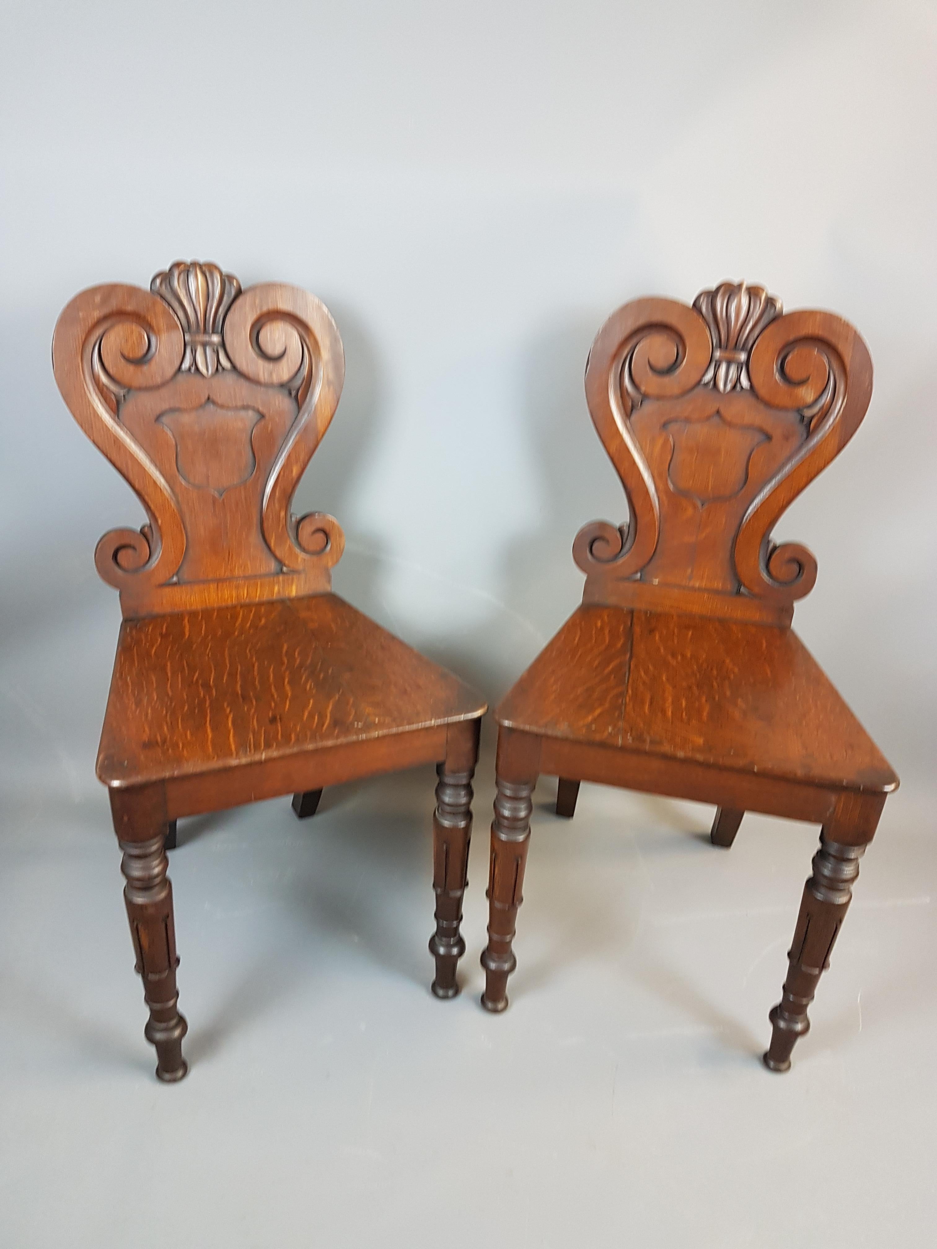 A very nice pair of 19th century William IV style oak hall chairs. These chairs are in very nice solid condition with only one leg having an old brass bracket on it, the quarter sawn grain on the oak gives a lovely decorative appeal to this pair.