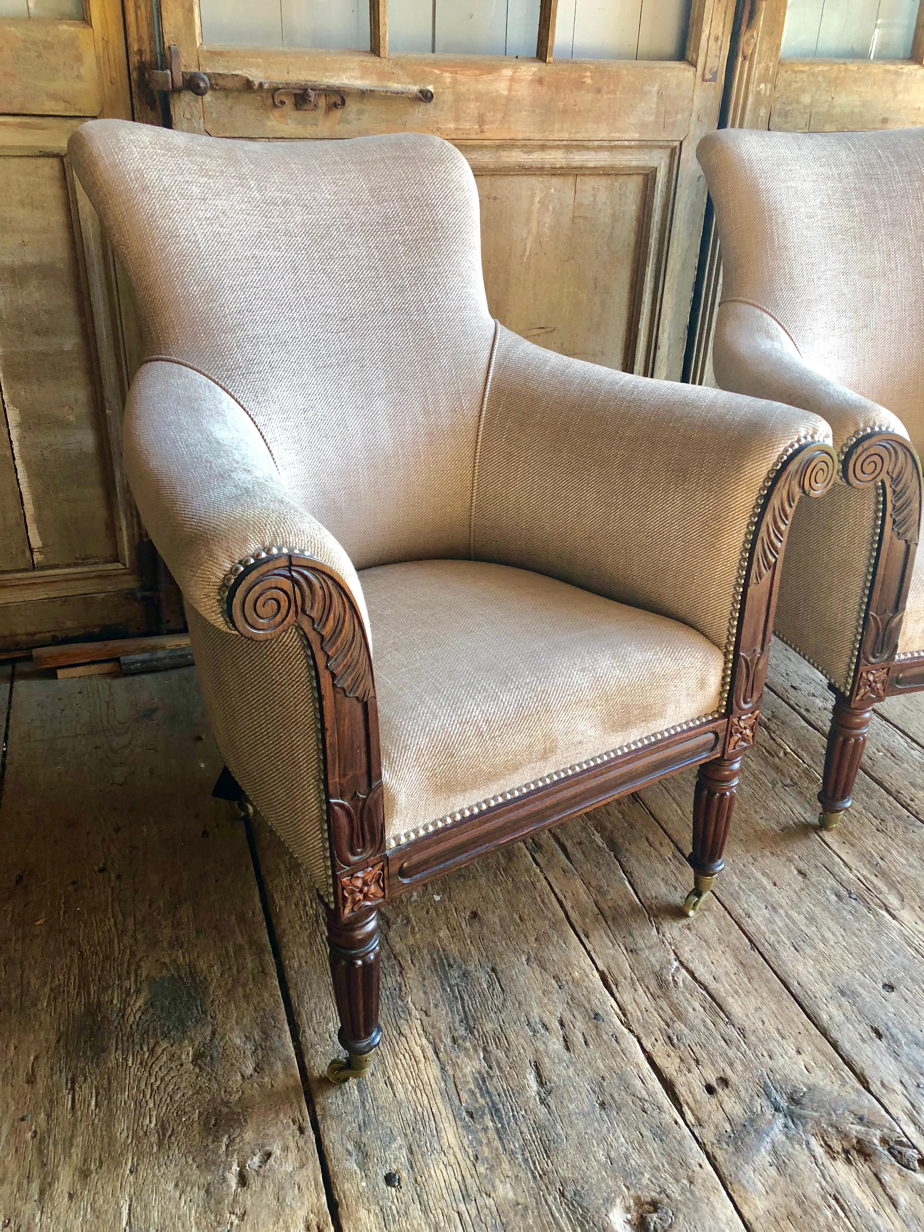 A pair of fine English William IV period rosewood bergeres or “lolling chairs”, circa 1830, with beautifully carved frames, upholstered in a cream cotton upholstery with silver decorative nail-heads. Feet are on brass casters. Sold: Sotheby’s June