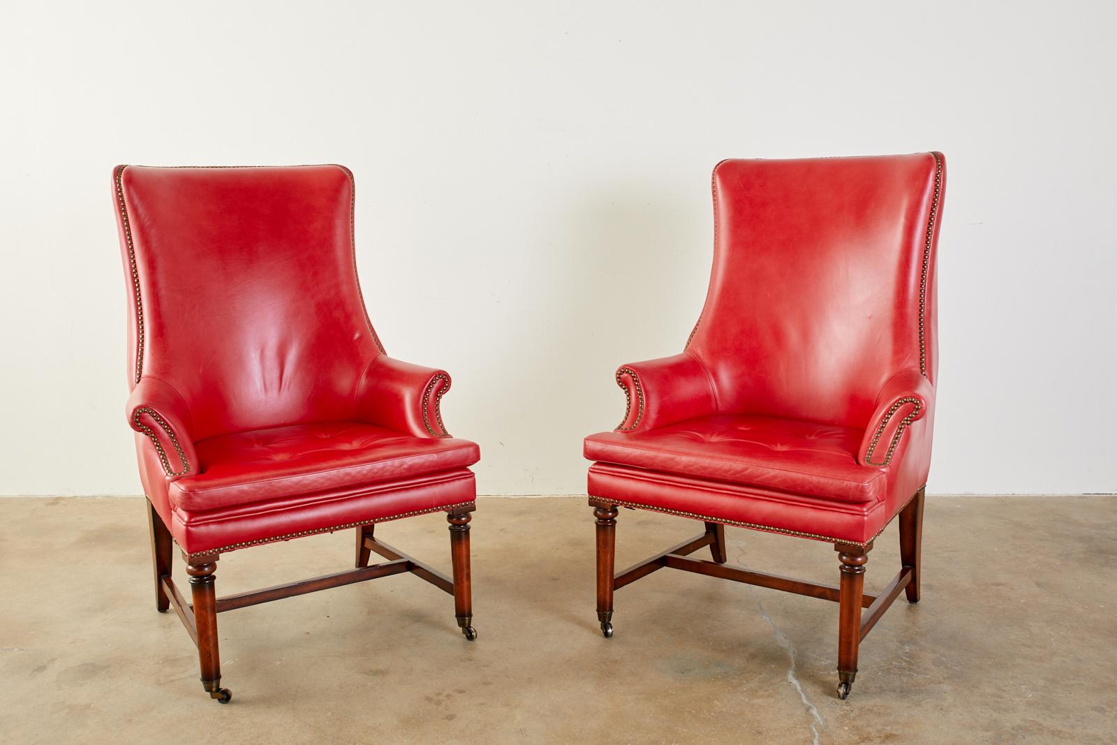 Distinctive pair of bespoke leather and mahogany library chairs or wingback chairs made in the English William IV taste by Barclay Butera Newport Beach, CA. The chairs feature a mahogany frame covered with stately red leather hides. The borders are