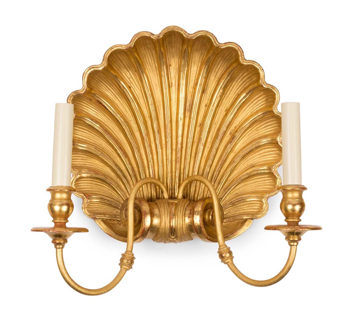 A pair of William Kent inspired shell form sconces carved in giltwood backplate issuing two candle arms with burnished gilt finish. Circa 1980. Measures: Height 14