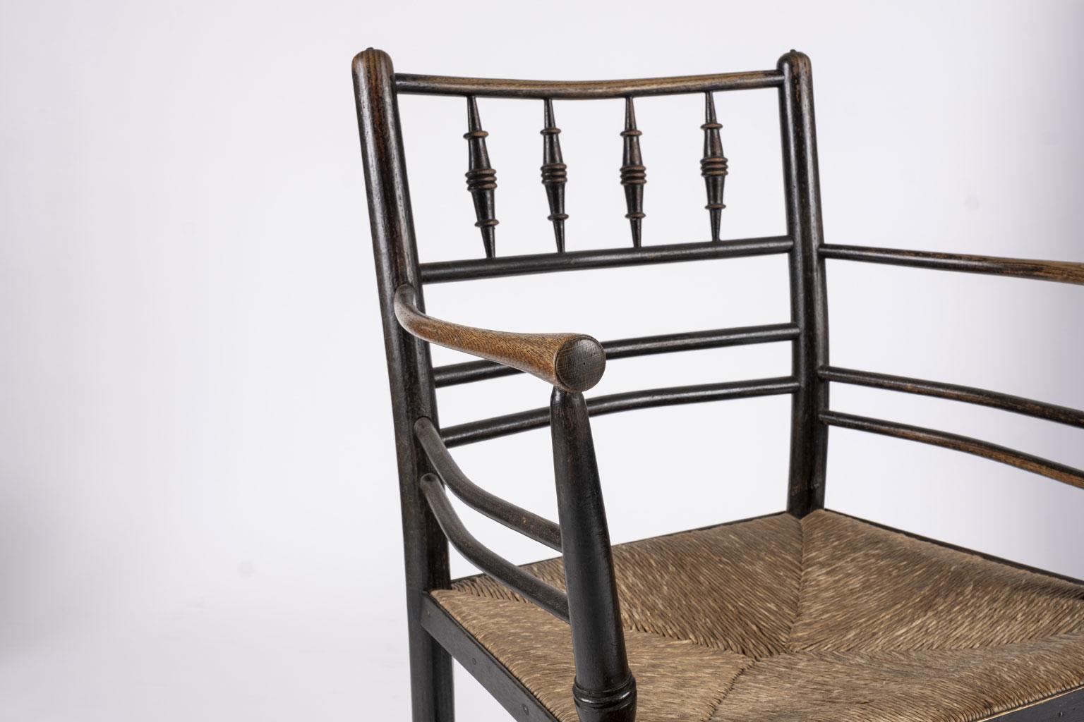 Pair of William Morris ebonized Sussex armchairs in excellent condition with original finish and early or original rush seats. These chairs (made by Morris & Co circa 1865-1885) are named after a type of country chair found in Sussex, which inspired