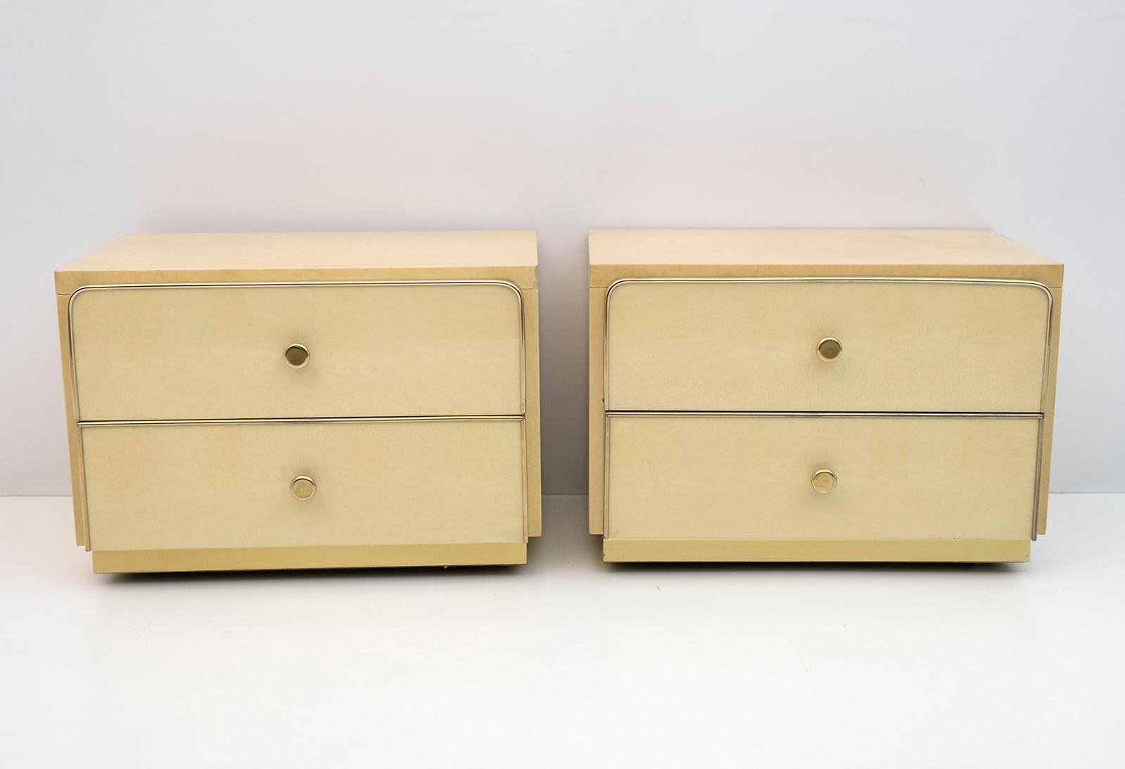 Beautiful pair of bedside tables of Italian manufacture in maple burl, the frames around the drawers and the band below are in brass and as feet they have retractable wheels, 1980s production, modernist design in the style of Willy Rizzo.