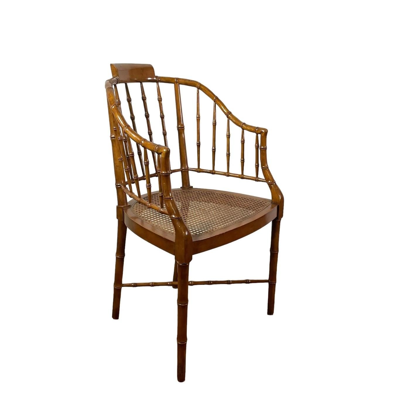 A pair of Windsor style faux bamboo and rattan chairs. Each chair has a tub shaped back with curved arms, a caned seat and an x-form cross stretcher. Chairs have Baker Furniture Company plaque.