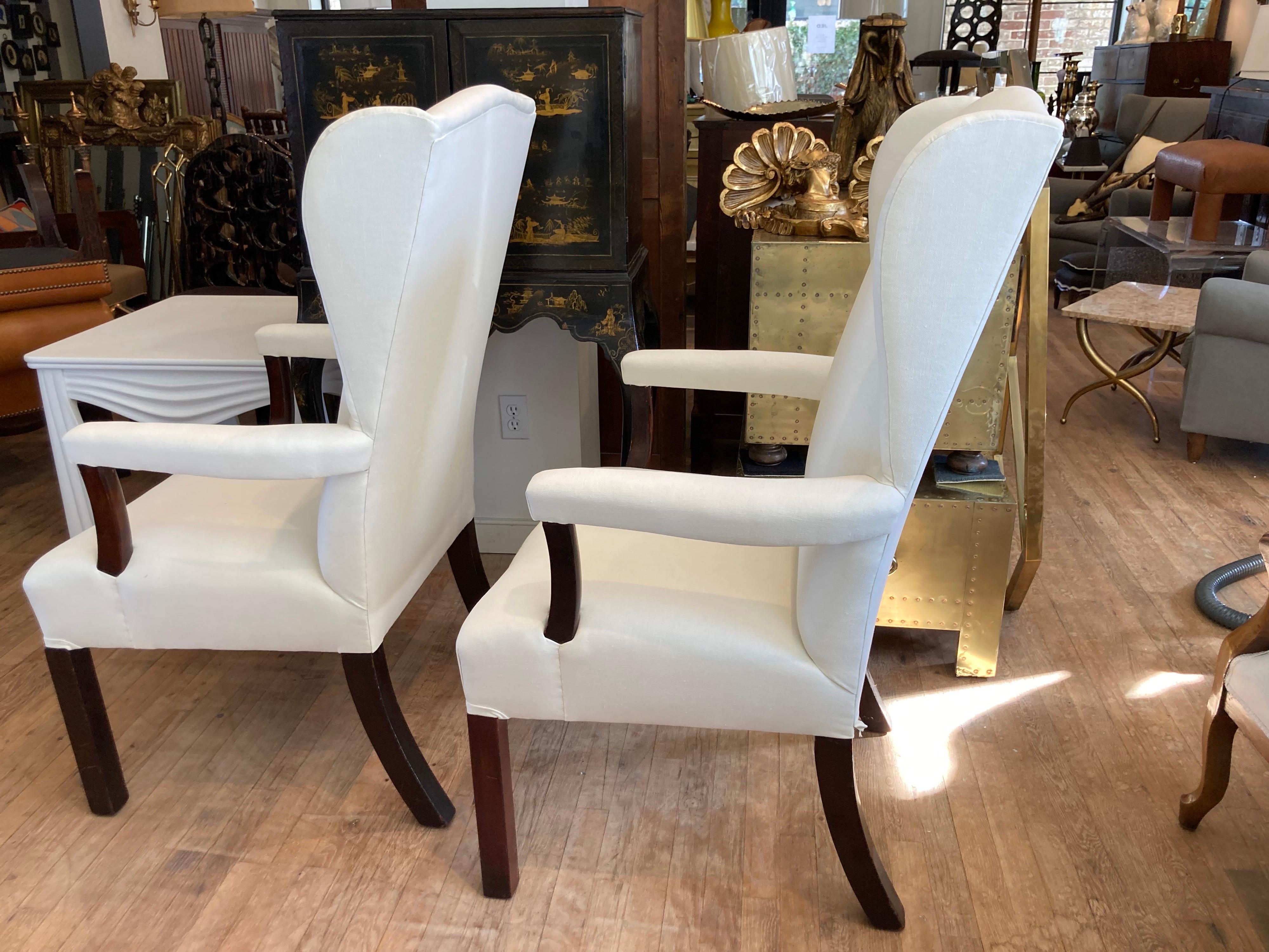 A great pair of open arm antique wingback chairs newly reupholstered in white linen.