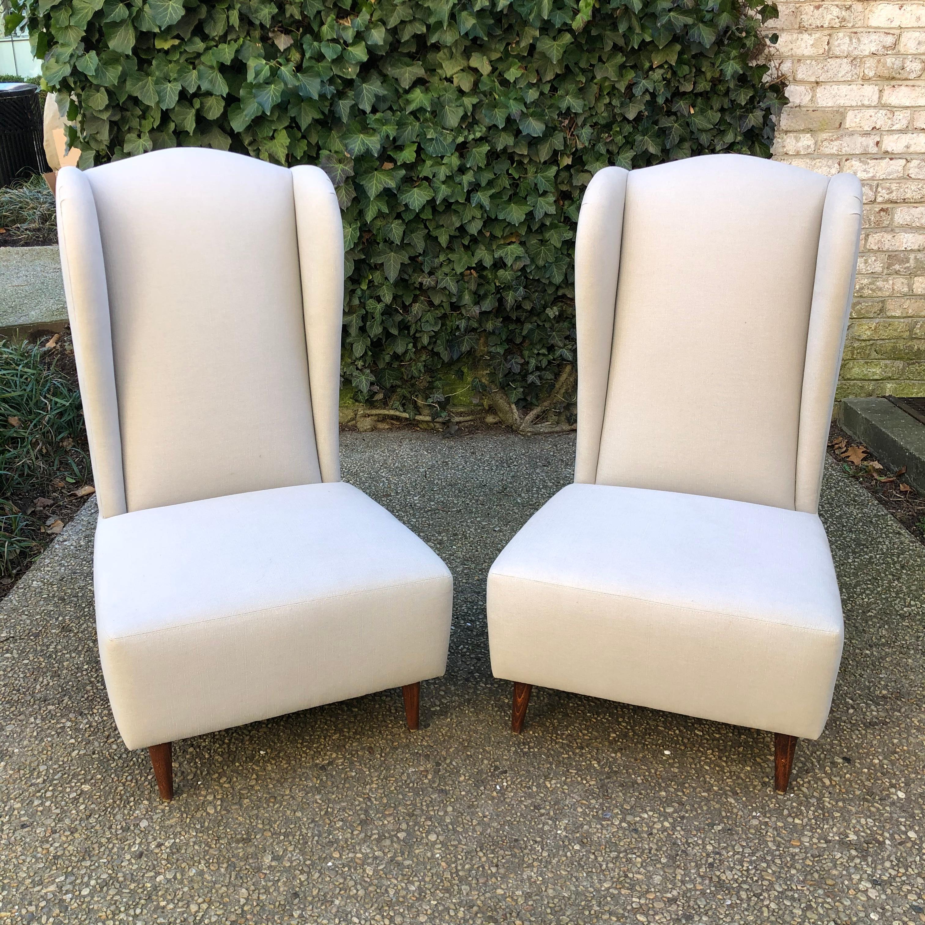 Unique pair of armless wing back slipper chairs newly upholstered in natural linen.