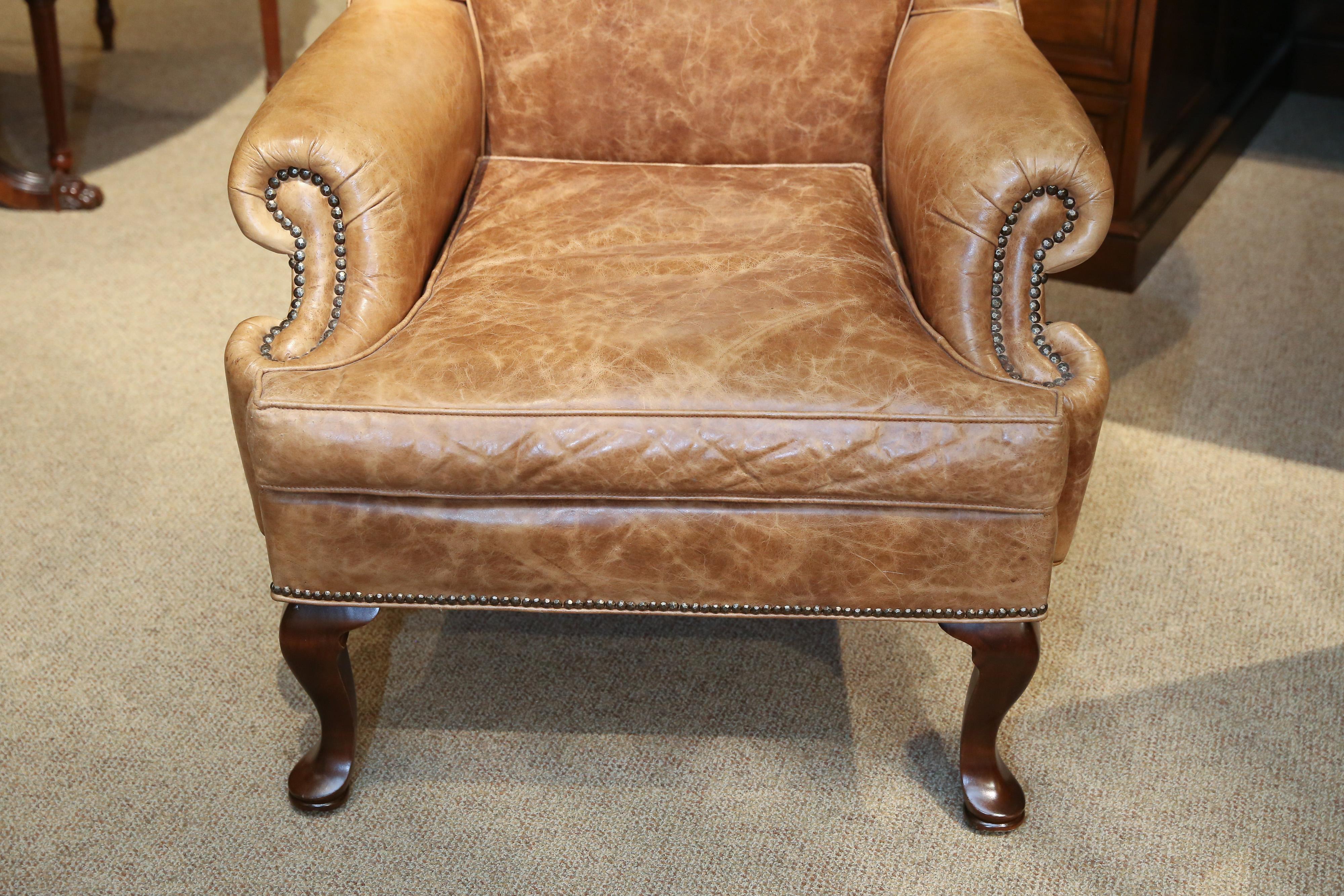 Soft gold color leather upholstered wingback chairs
Each with a serpentine seat cushion and cabriole legs
with pad feat. Trimmed with brass tacks.