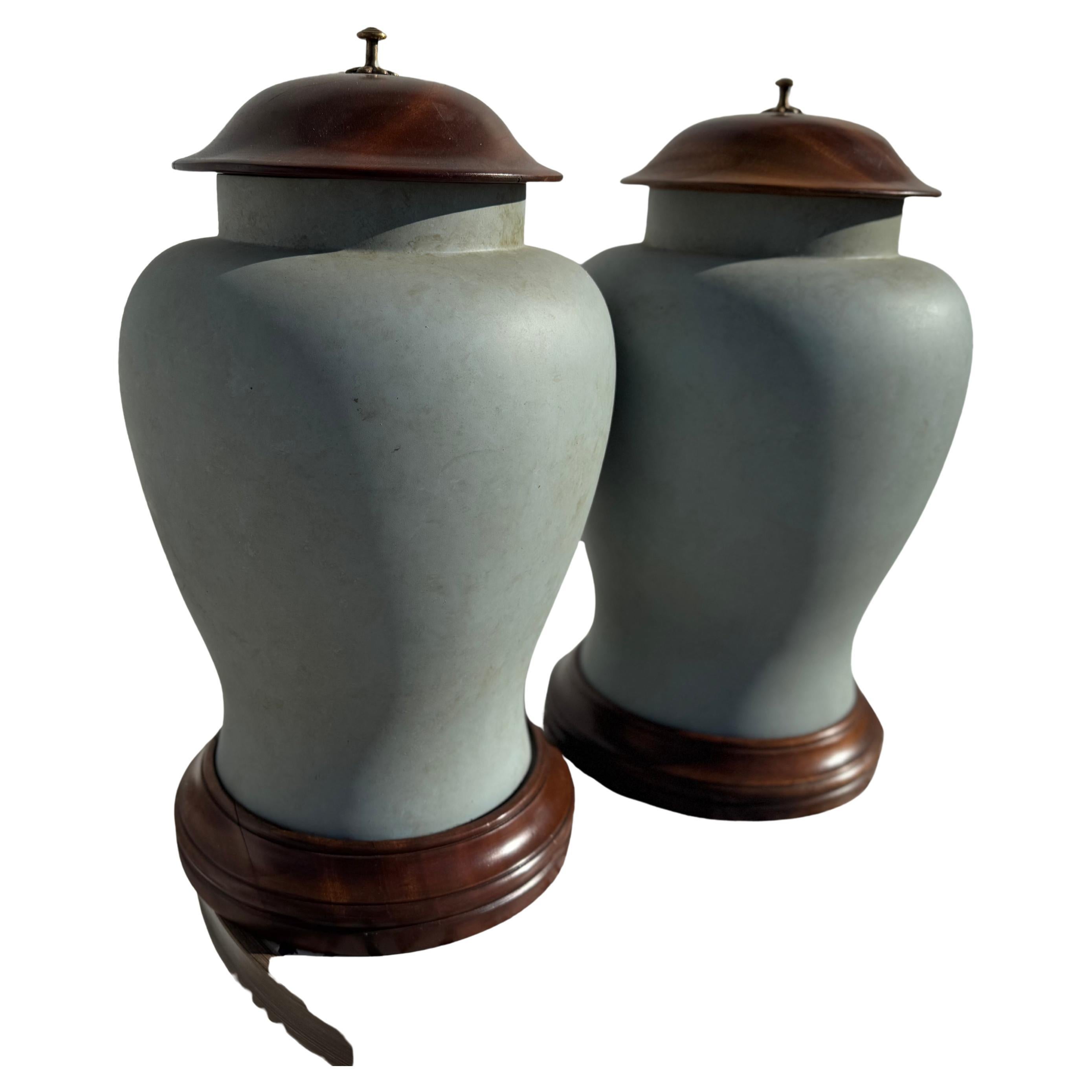 This is a modern pair of unique looking urns.
The urns are made of a heavy plastic and have solid wood lids and bases.
The urns inset into the wood bases.
The lids are acorn shaped.