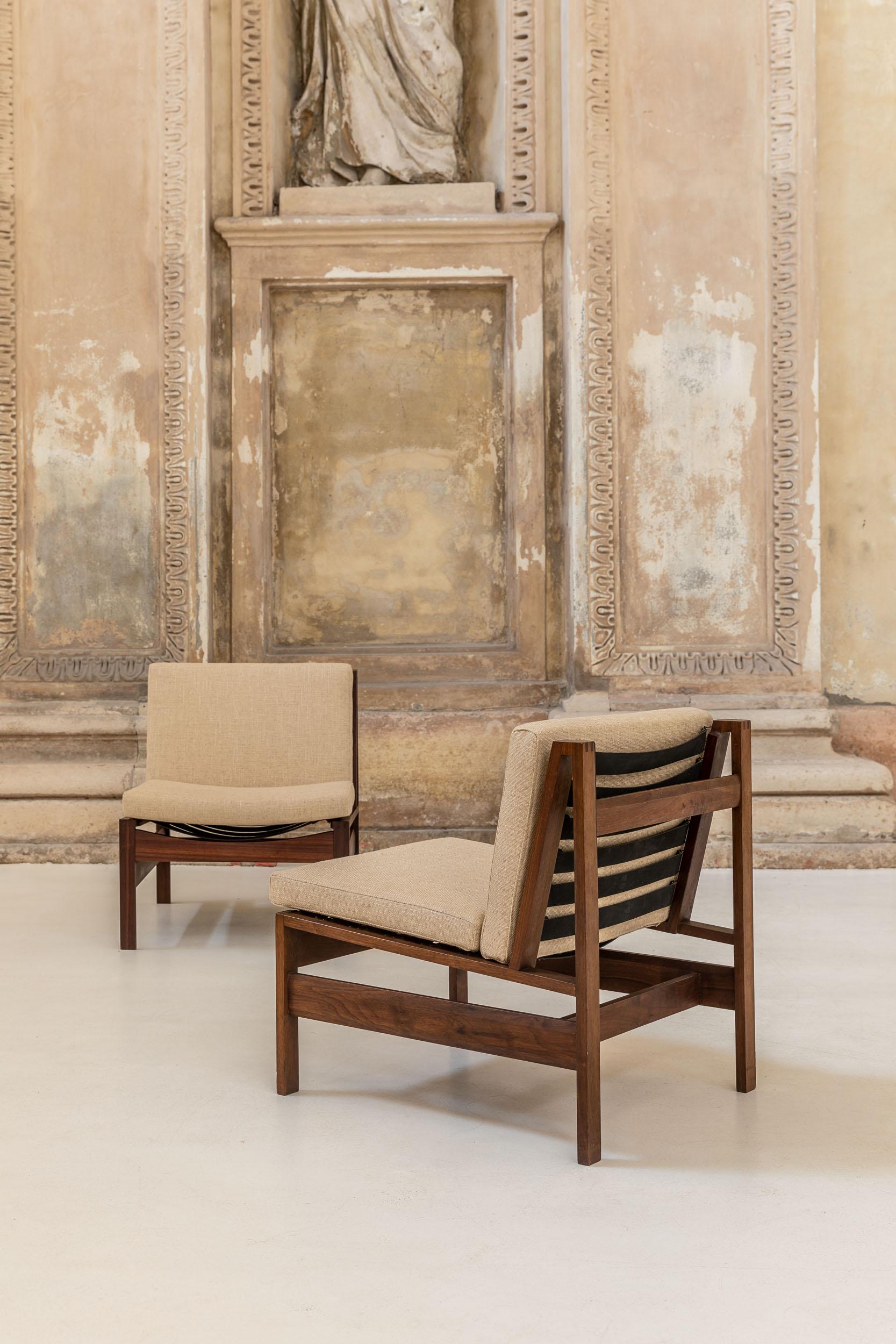 Pair of low seating armchairs in wood structure. The seating is really comfortable due to the elastic black stripes and the two cushions in écru color.
Different beautiful details in linear and squared shapes, are visible from any side of the chair.