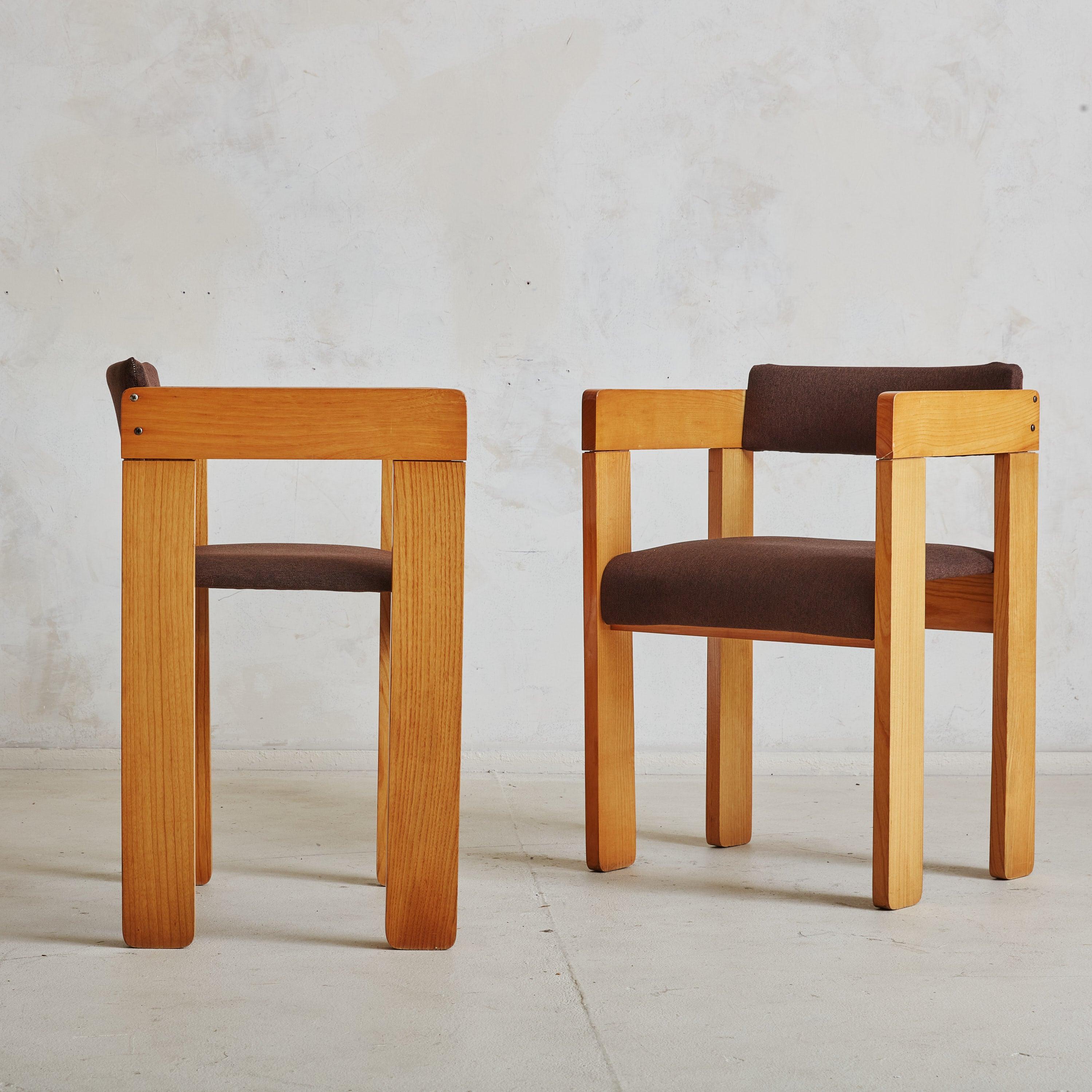 A pair of 1960s Italian armchairs featuring minimalist solid wood frames with angular arms and rectangular block legs. The blonde wood frames contrast beautifully with the chocolate hued upholstered seats, which extend slightly down the front side
