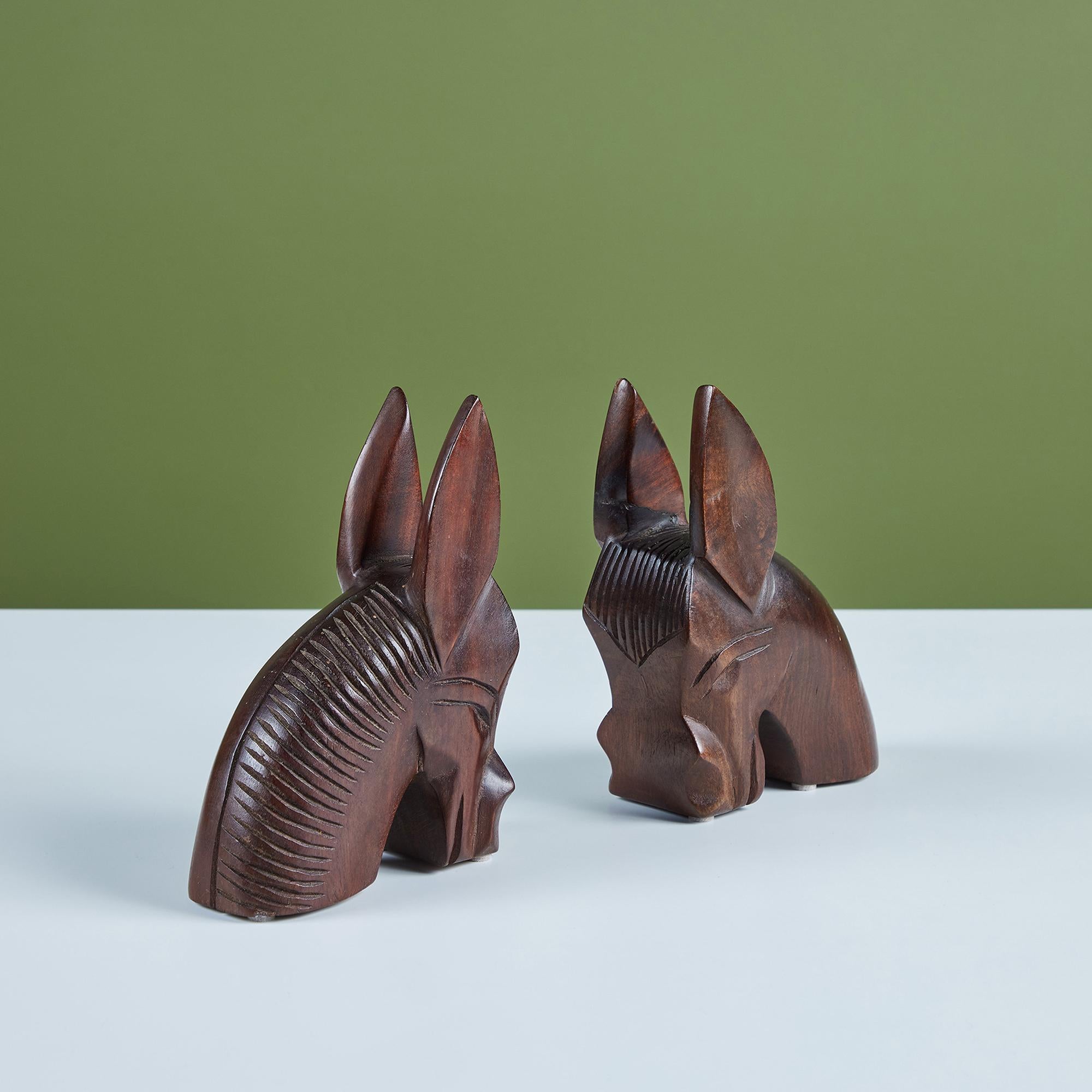 A pair of solid wood bookends hand carved into the shape of donkey heads. Each donkey has ears that stand at attention and a dark walnut finish. Marked Made in Haiti -1953.

Dimensions
Each bookend measures: 4.75