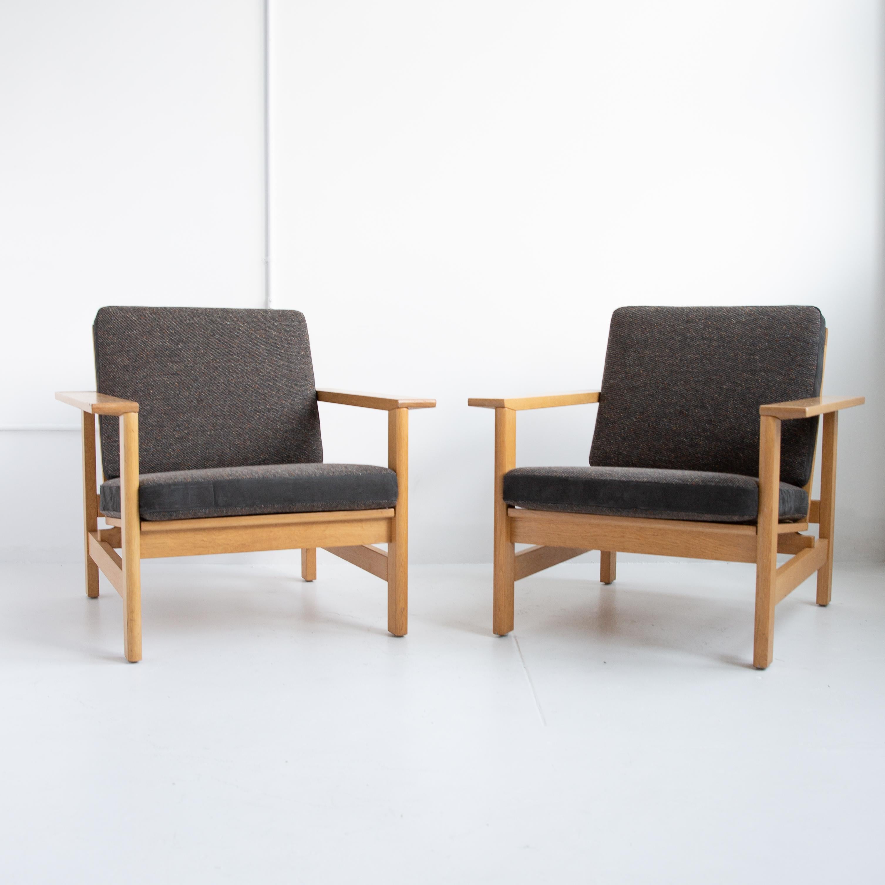 Handsome pair of Soren Holst lounge chairs with solid oakwood frames and newly reupholstered seat cushions featuring a beautiful charcoal fabric and suede on the sides. The structure and beautiful joinery of the Danish designer's work reflects his