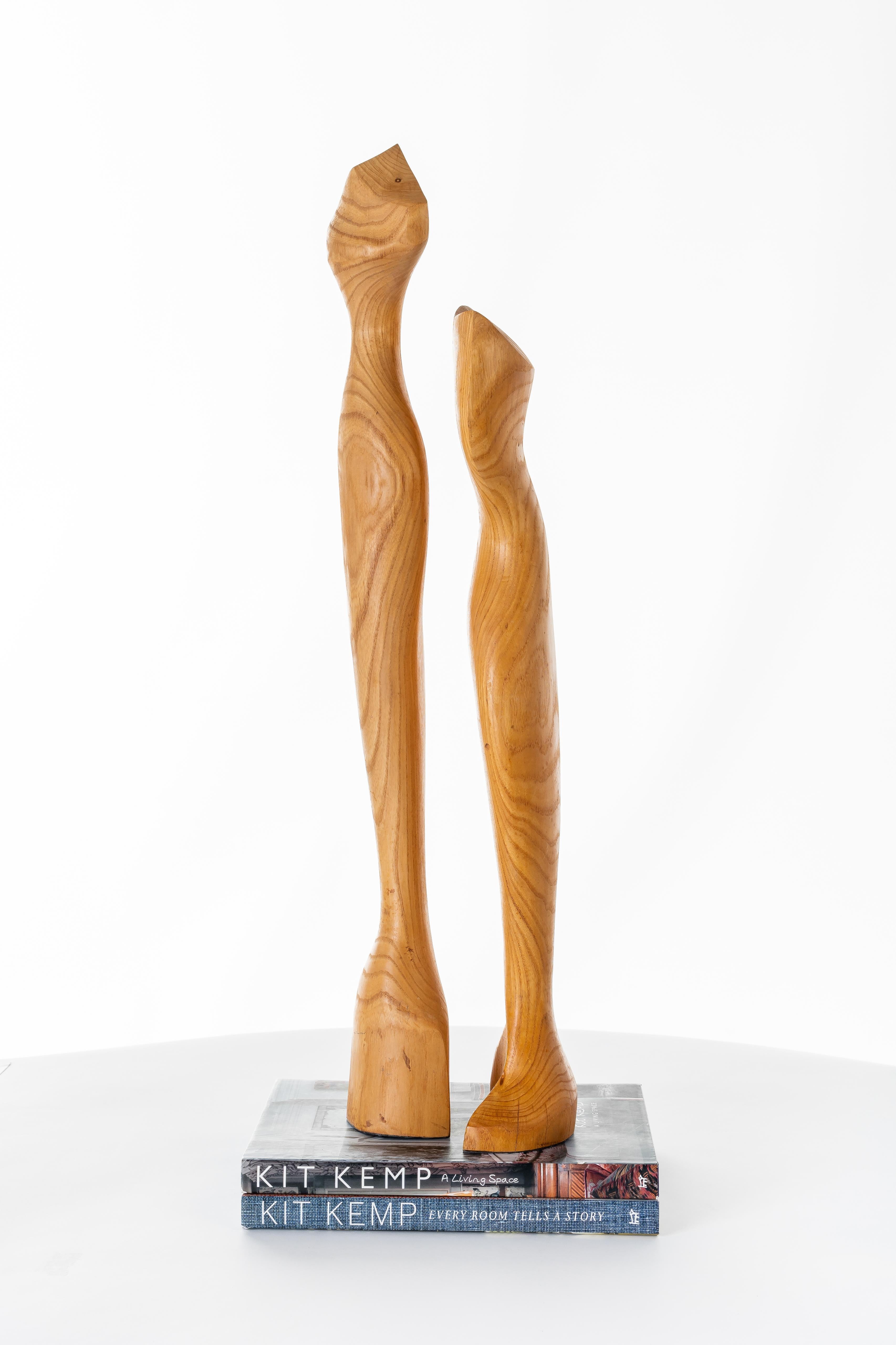 Pair of carved wooden sculptures, each offering a unique Silhouette accentuated by natural wood grain details.