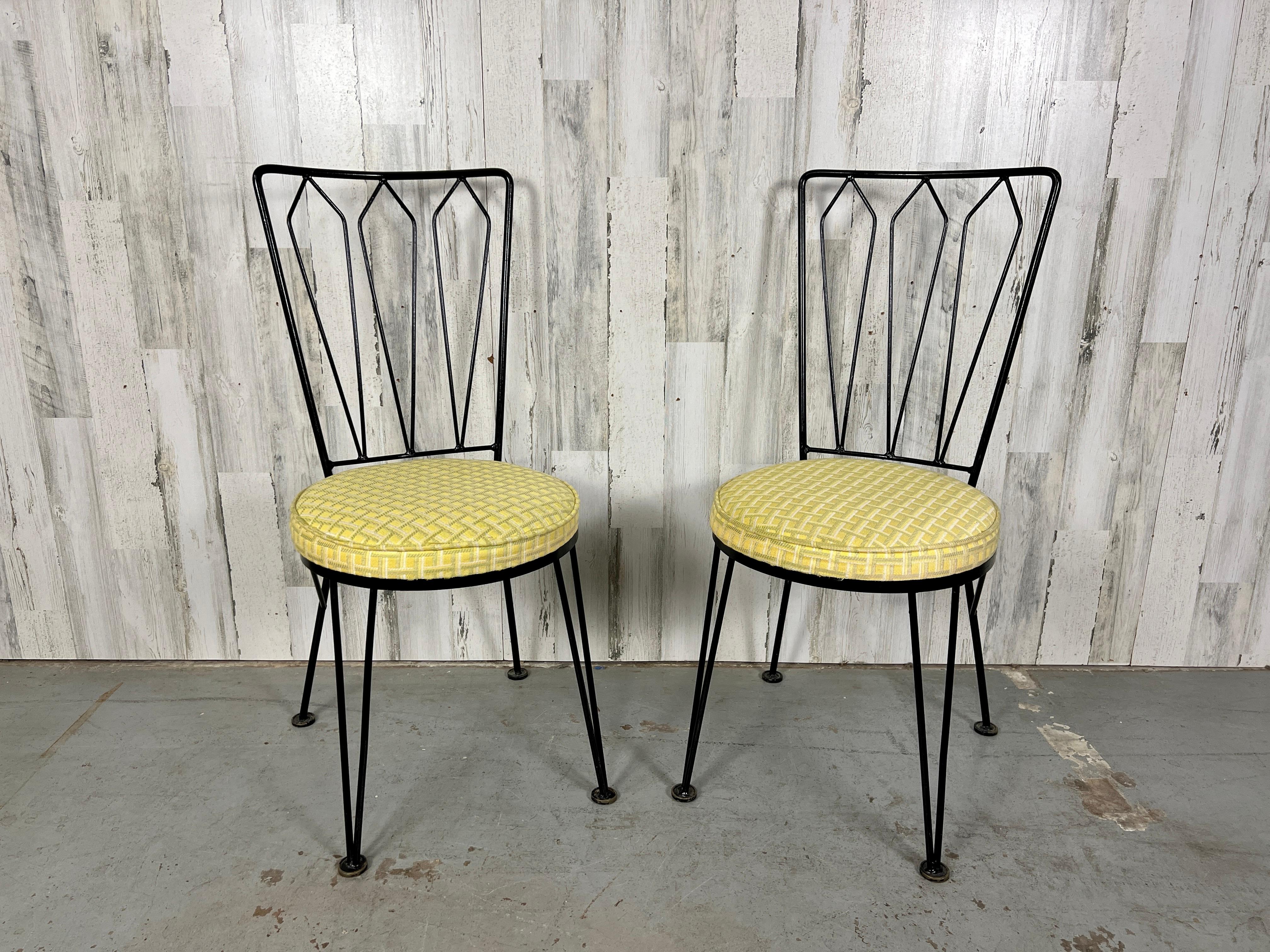 This set of Mid-Century Modern wrought iron dining chairs has the look of Salterini but are made by the Woodard group. Woodard was a high end company in the 1950s.  The original black finish to the wrought iron frame is worn. 