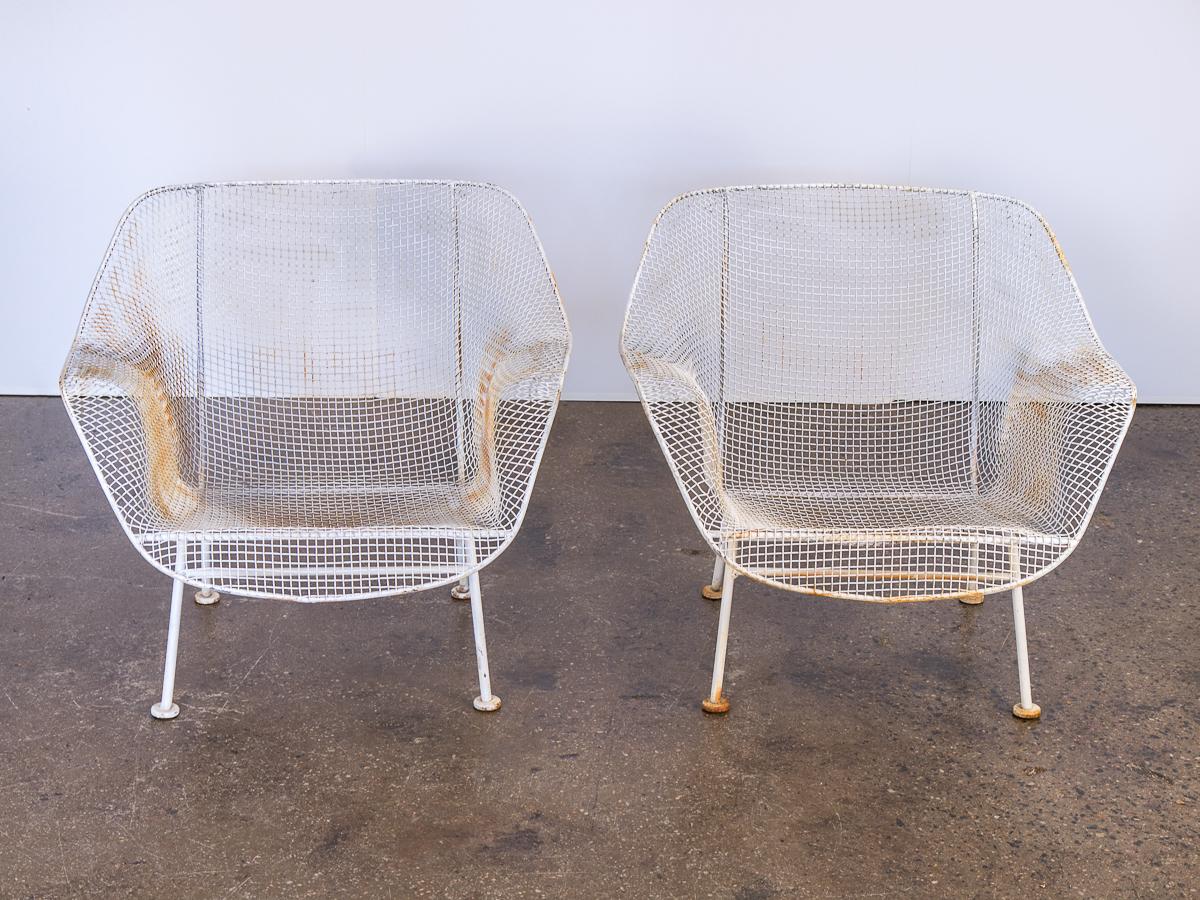 1950s Pair of Woodard Sculptura garden lounge chairs. These hard to come by chairs feature a low-slung design for patio or deck lounging. The wrought iron frames and woven mesh steel seats are strong and can stand all weather. White enamel finish