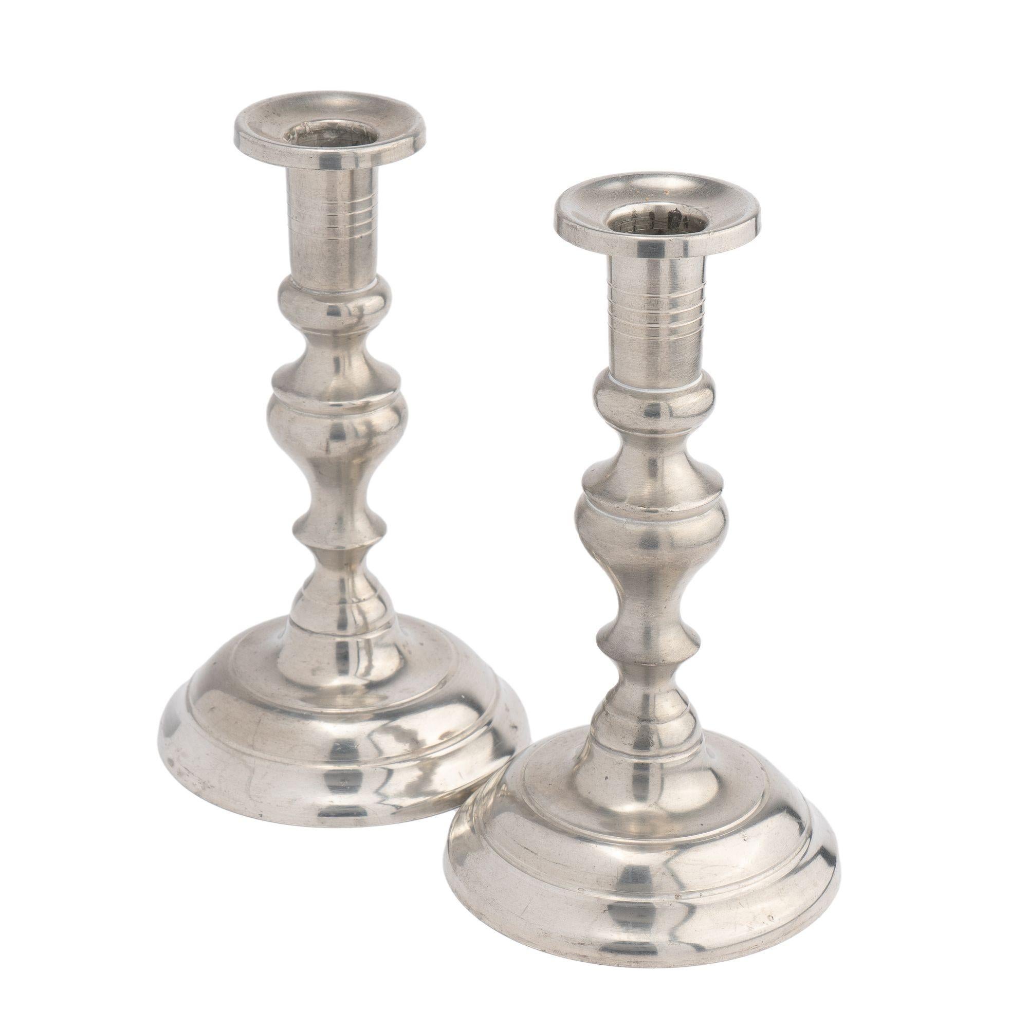 Pair of Colonial Revival circular dome base pewter candlesticks with an inverted baluster shaft and elongated urn form candle holder. After an 18th century English model. Makers stamp on the underside of the base.

American, Woodbury, Connecticut,