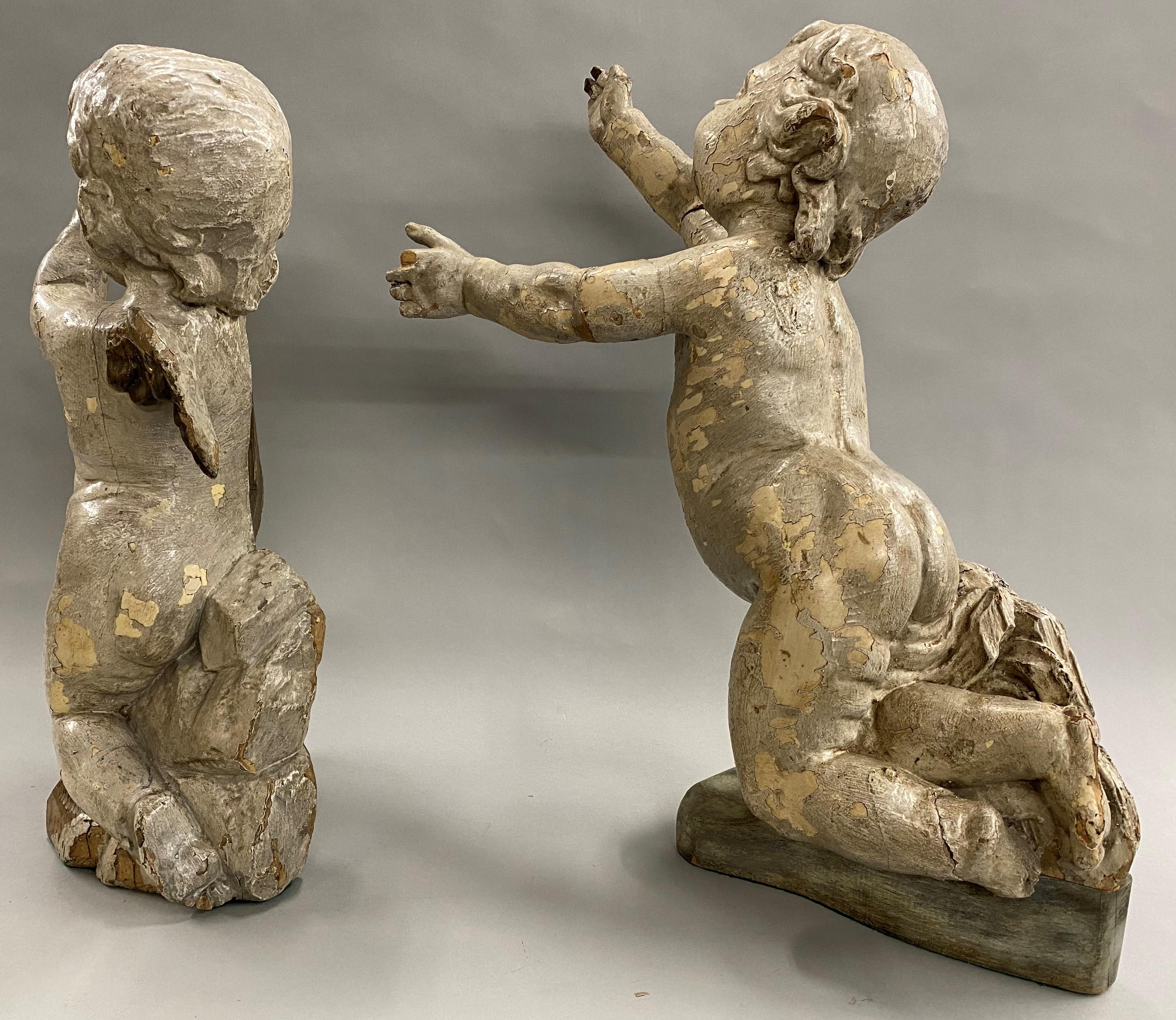 A fine pair of architectural solid wooden carved winged putti with paint and gesso surface, one in a praying position and one with outstretched arms and legs. Probably Venetian, dating to the 17th century in good overall condition, with some paint