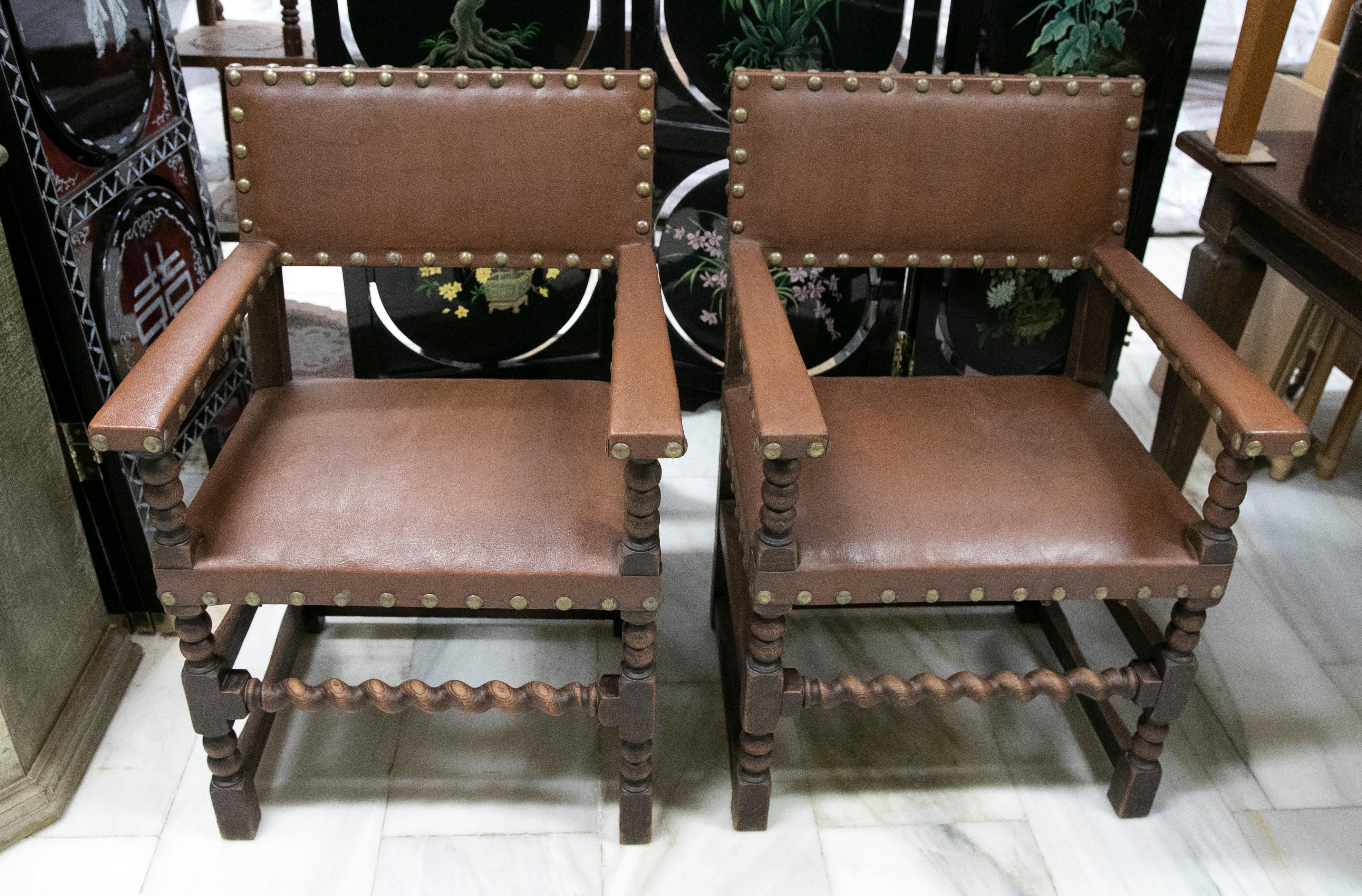 Pair of wooden armchairs with studded leather seat and backrest.