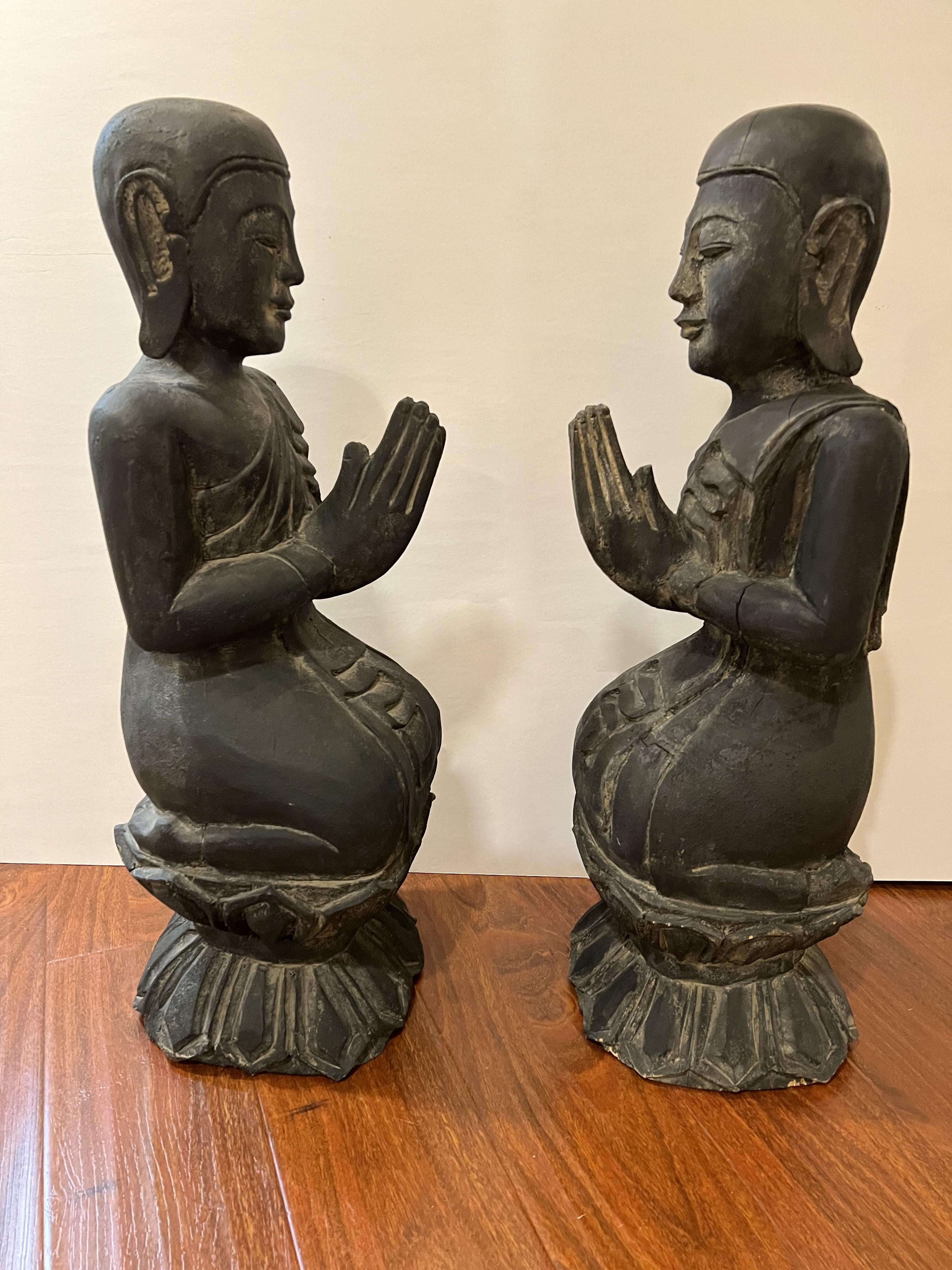 A pair of wooden Buddha sculptures. One is a man, and the other is a woman. 
From my research, this could either be a buddha sculpture or a monk sculpture. 
They are seen to be kneeling and praying on top of an acanthus pedestal. 
They are