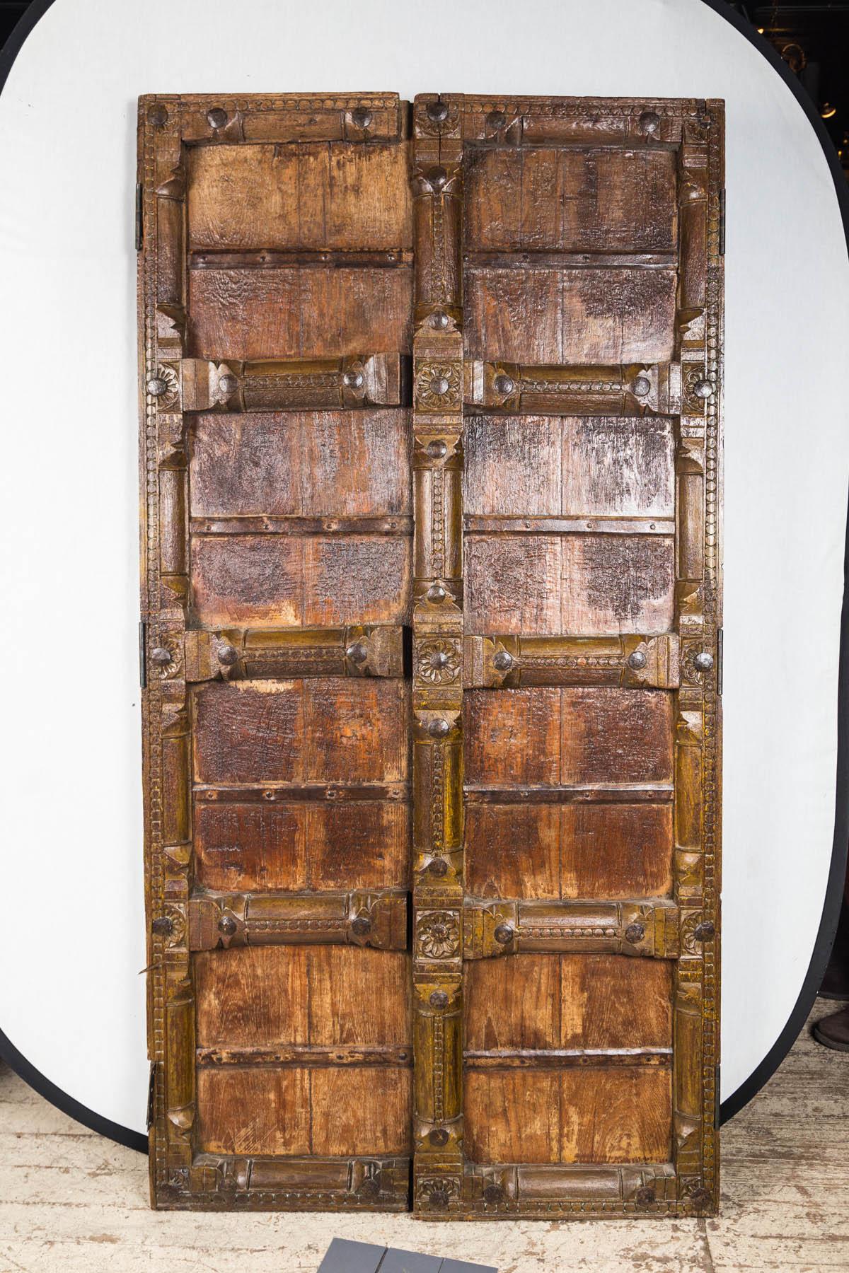 This pair of doors are handmade and heavy. There is no lock, never was. Iron straps and nails can be seen on the back. There is no evidence of any pulls. Cross bars and verticals are simply carved. There are hinges on both.
We have not been able to